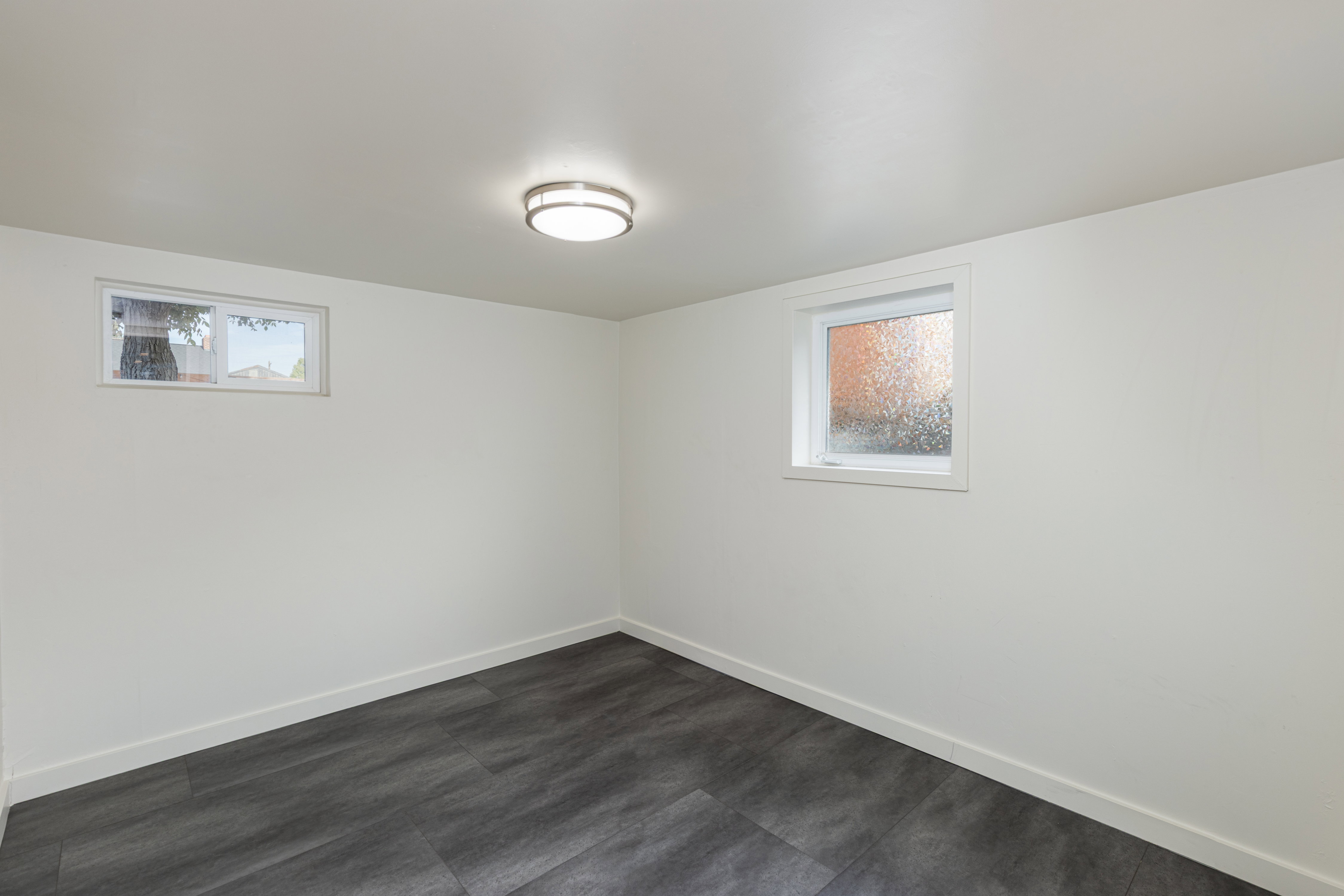 Spacious room featuring wood-finish flooring, white baseboards, and a neutral wall color