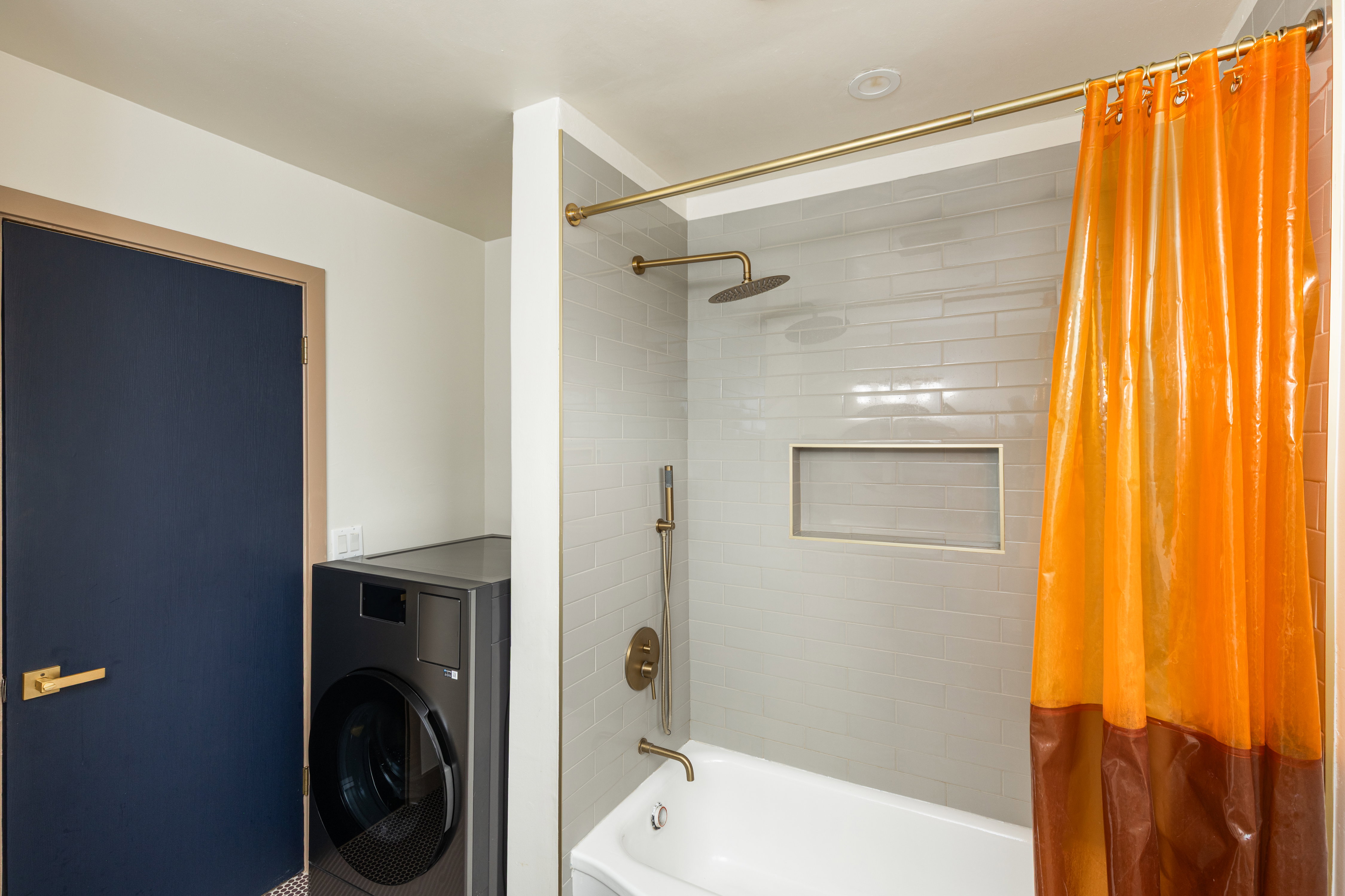 Bathroom featuring white subway tile surround with recessed niche, a soaking tub, and brass-finish fixtures