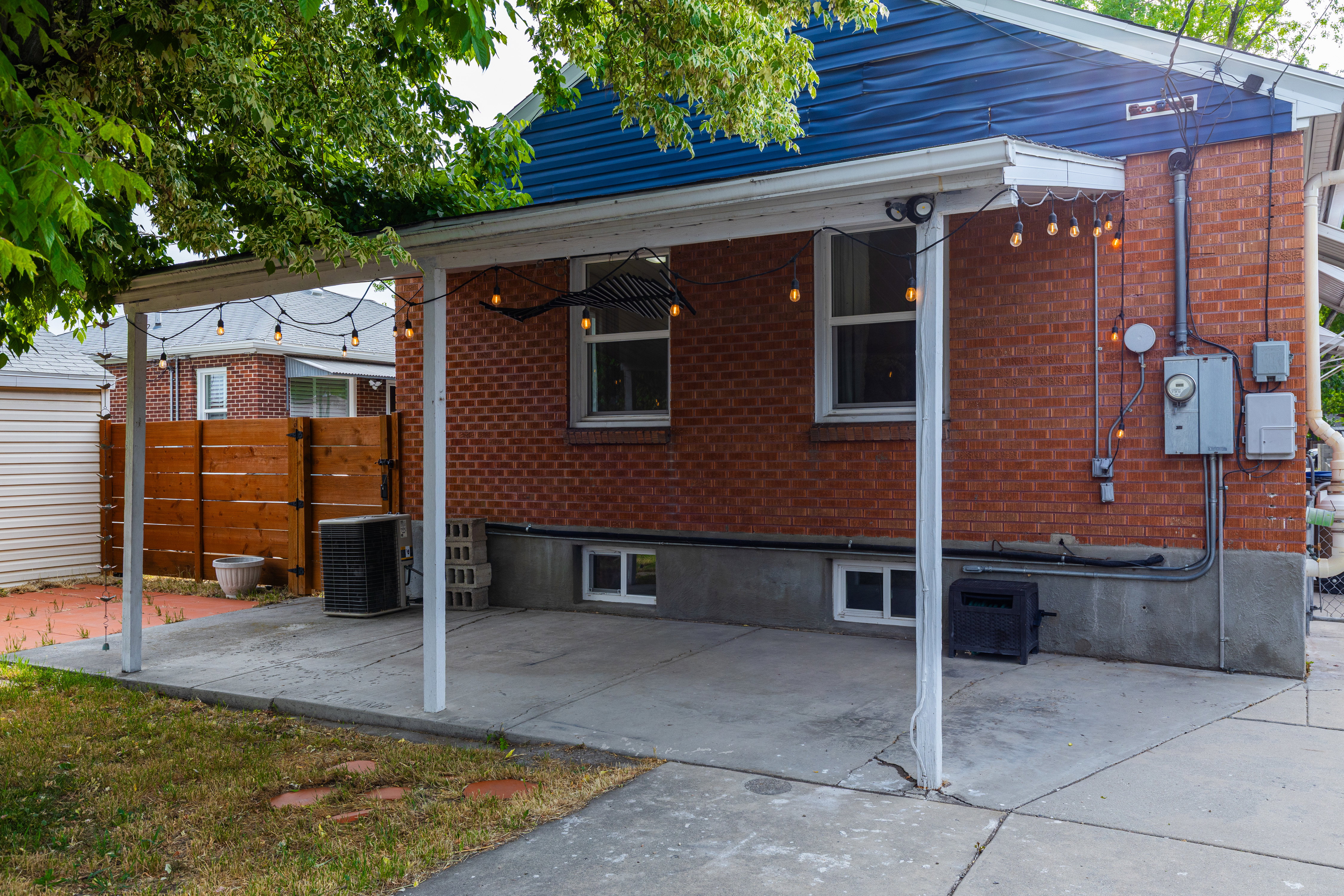 Covered concrete patio with brick exterior and blue siding