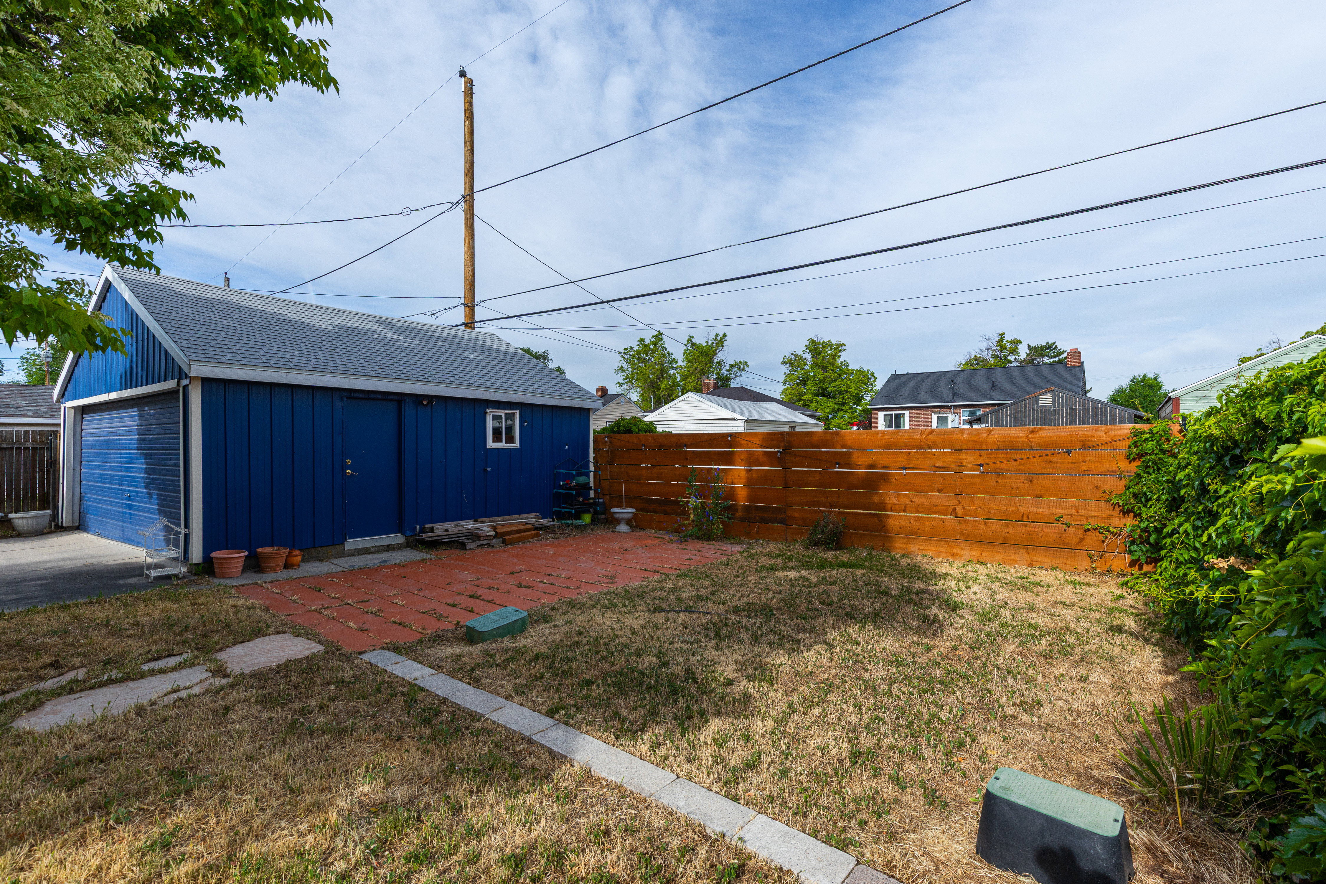 Detached garage with blue siding and a light gray shingle roof, featuring a single garage door and an additional entry door