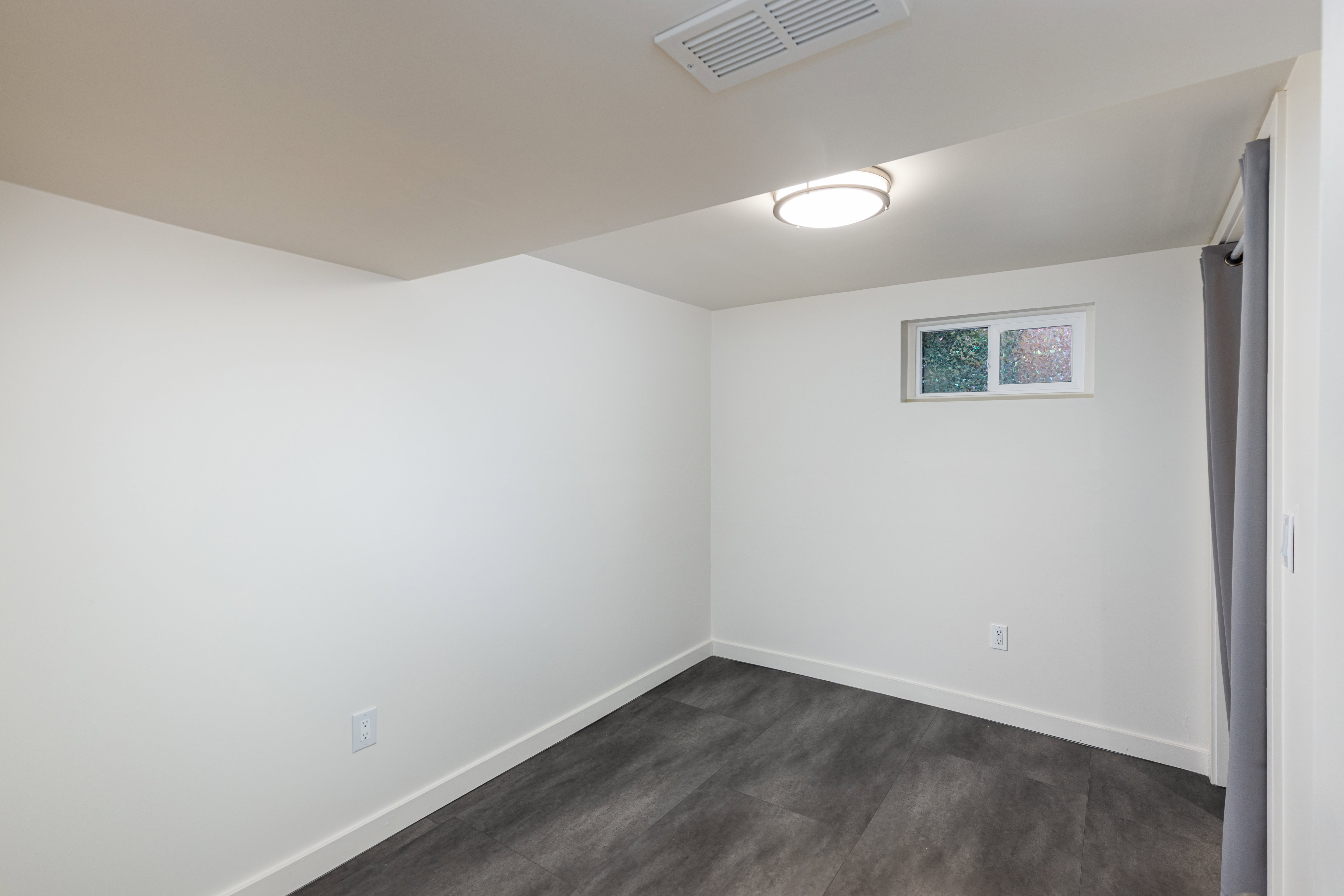 Interior space featuring light-toned walls, dark wood-finish flooring, and a flush-mount ceiling light