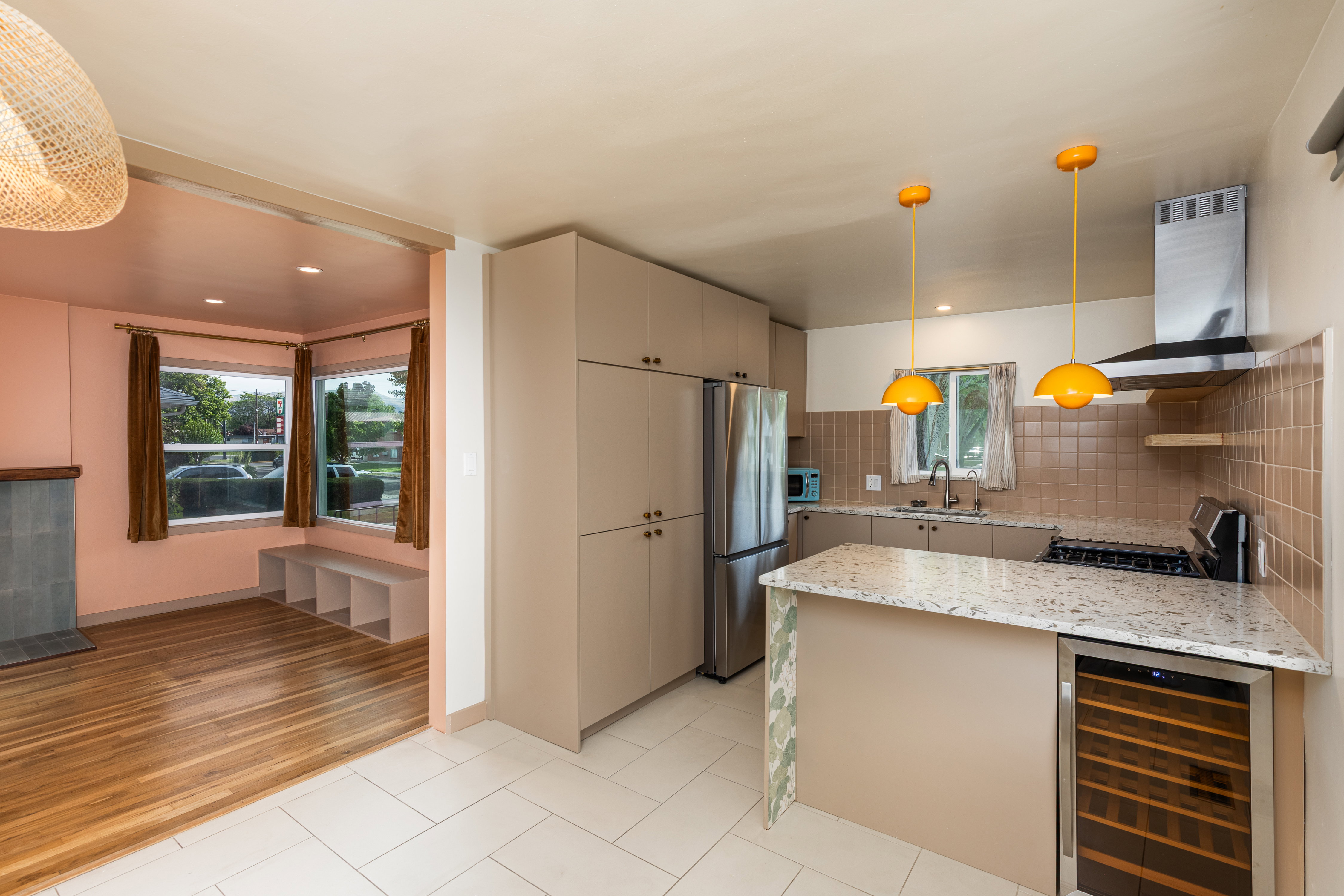 Modern kitchen featuring light-toned cabinetry, stainless steel appliances, and a central island with a built-in beverage cooler