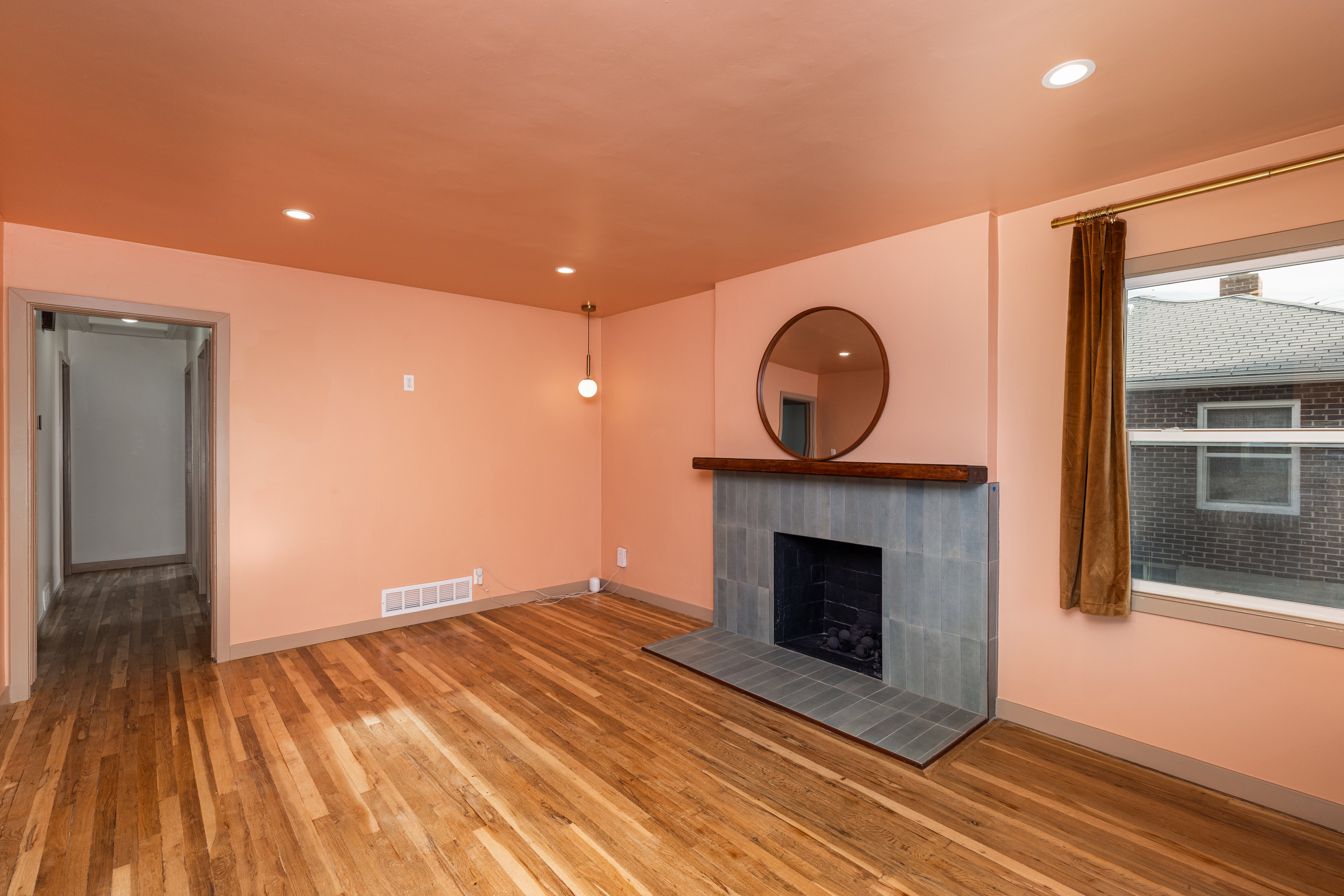Living area featuring a tile fireplace with a wood mantel, wood-finish flooring, recessed lighting, and a pendant light fixture