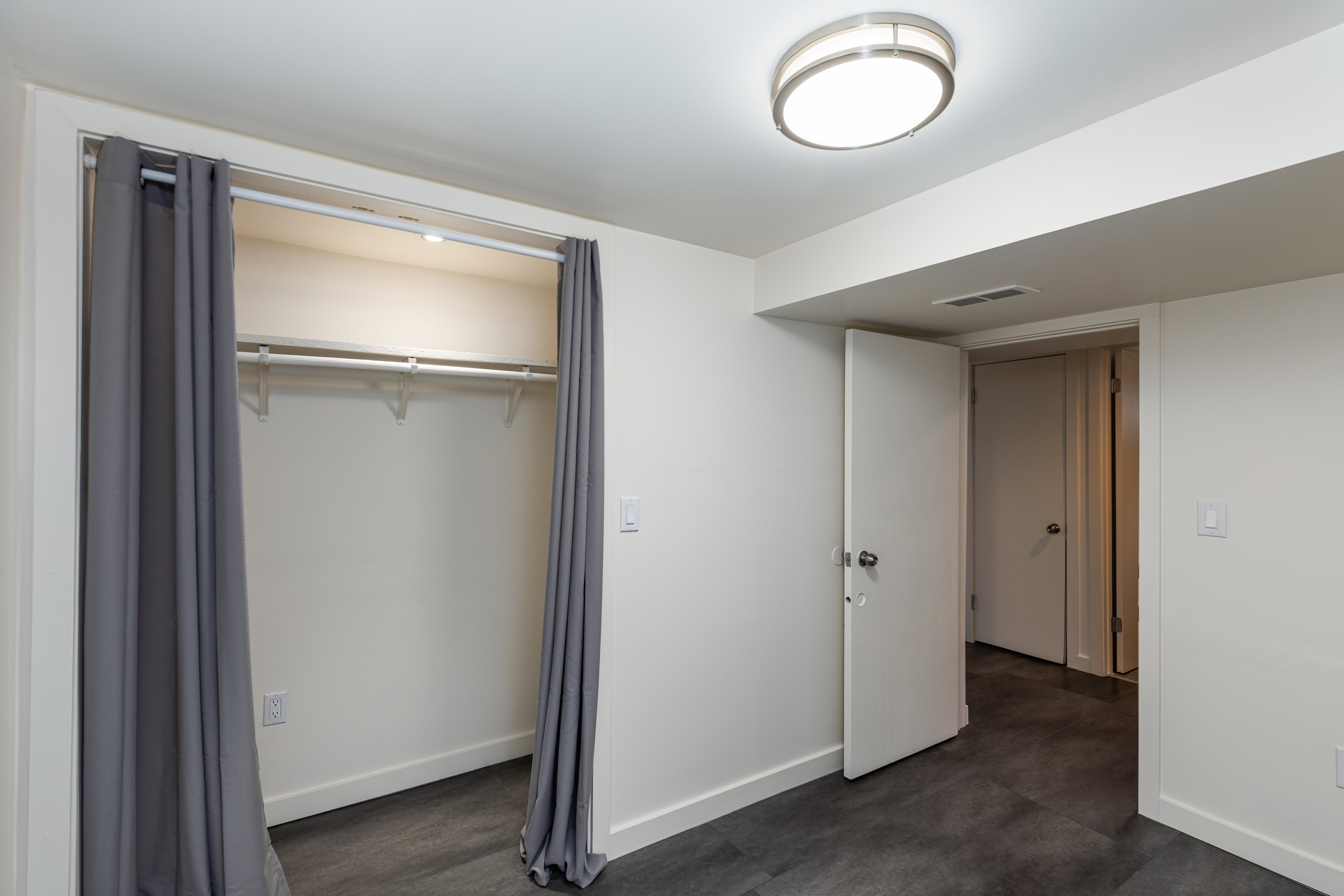 Room featuring dark wood-finish flooring, white walls, and a contemporary flush-mount ceiling light