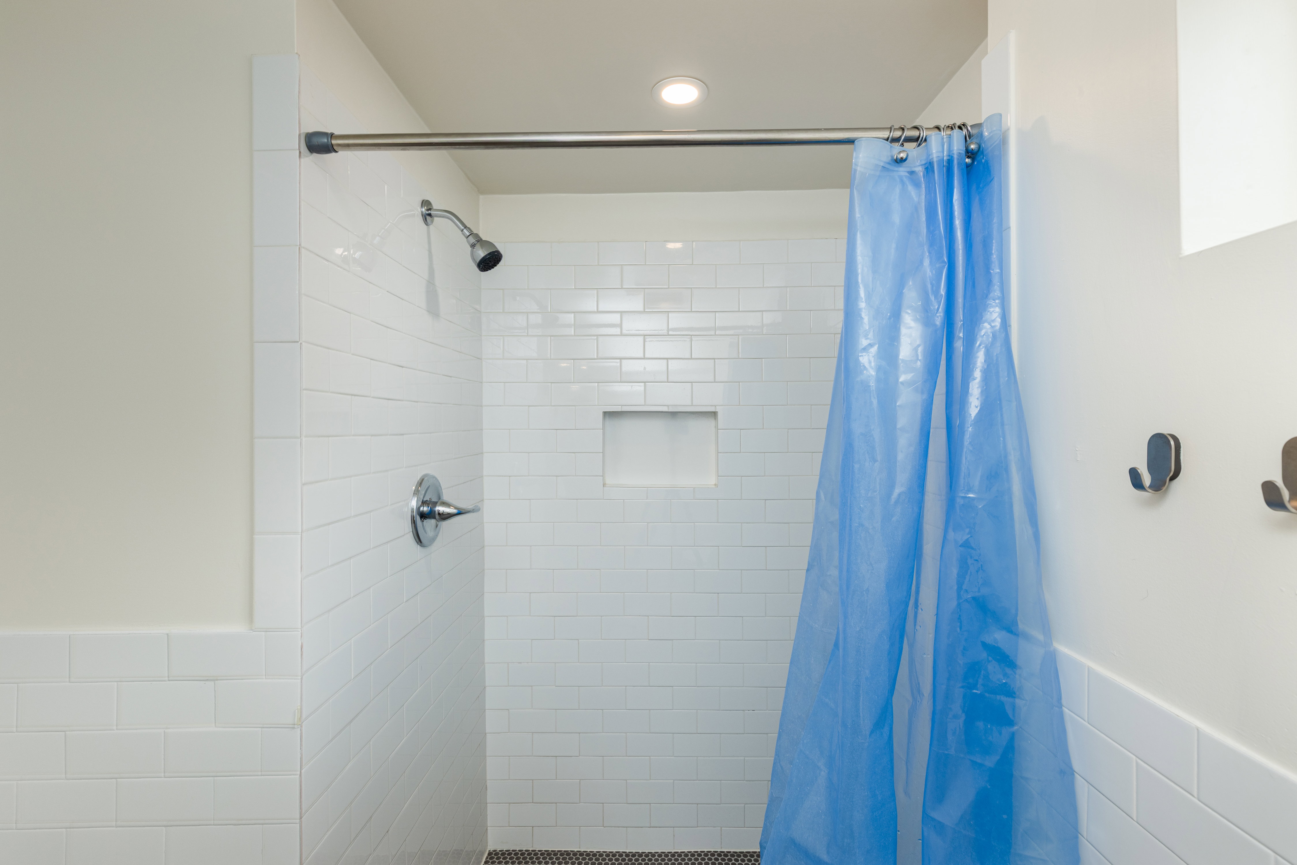 Shower with white subway tile walls, a built-in niche, and a dark mosaic tile floor