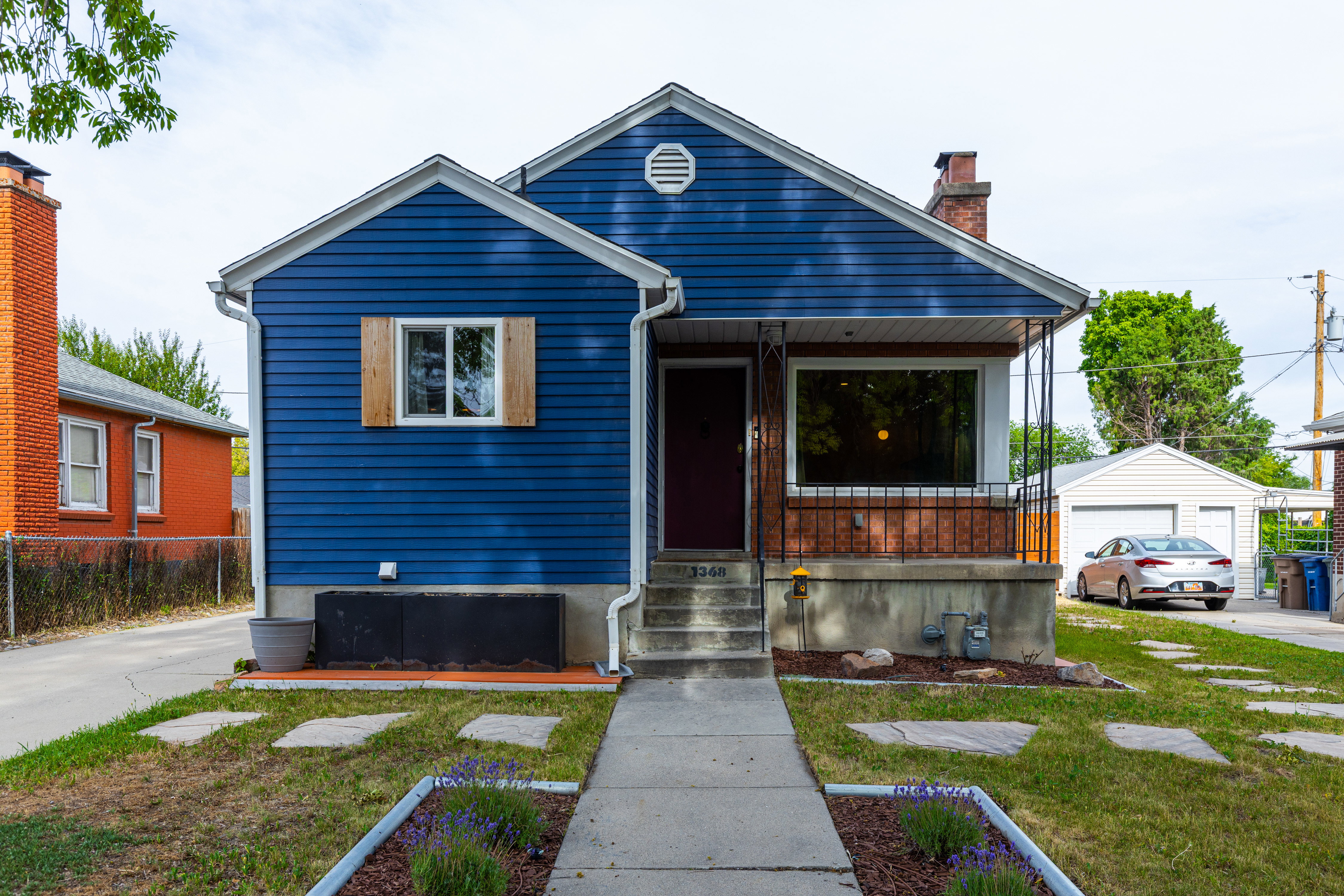 Blue siding exterior with white trim, a covered porch, a prominent bay window, and a detached two-car garage