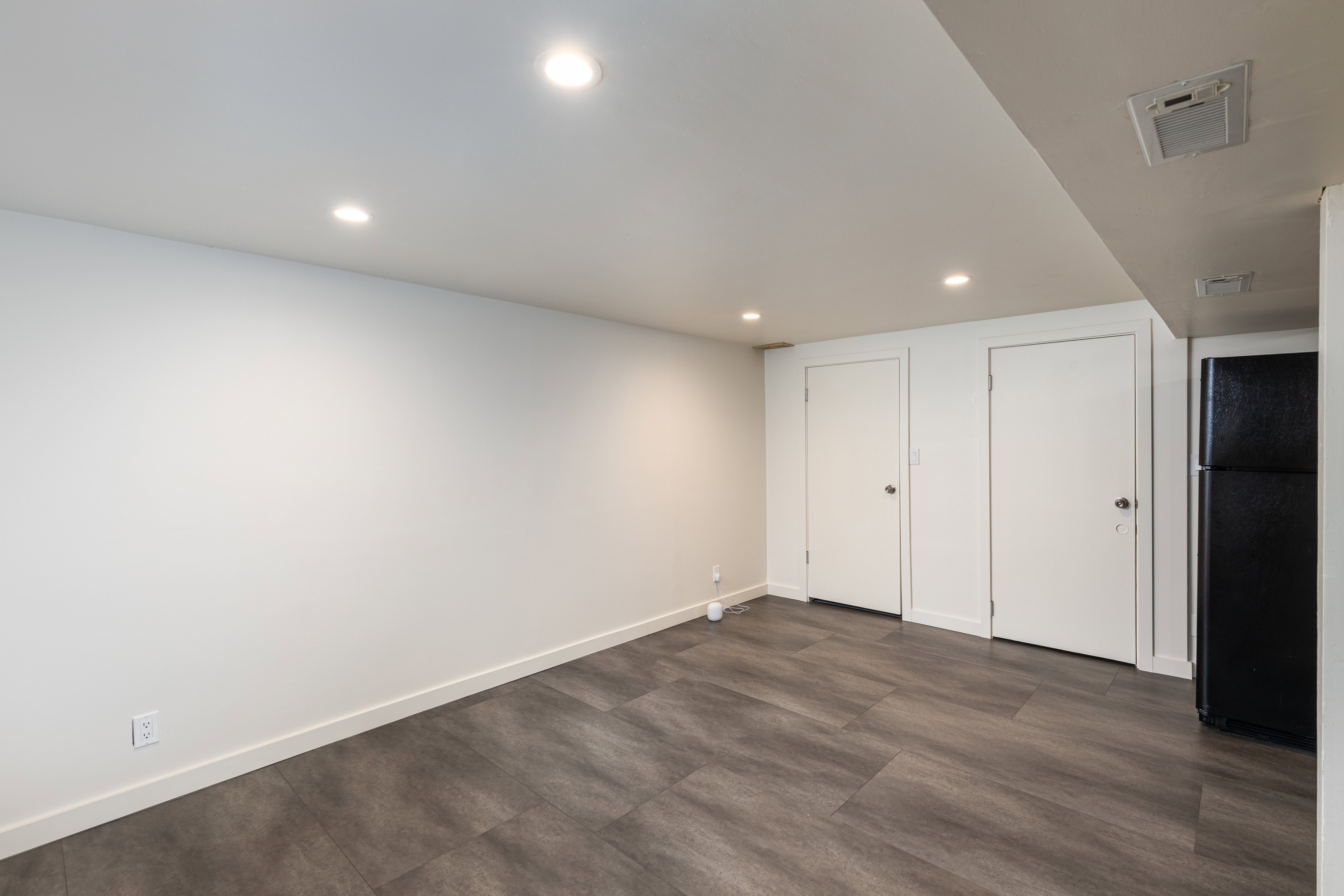 Spacious room featuring wood-finish flooring, recessed lighting, and bright white walls