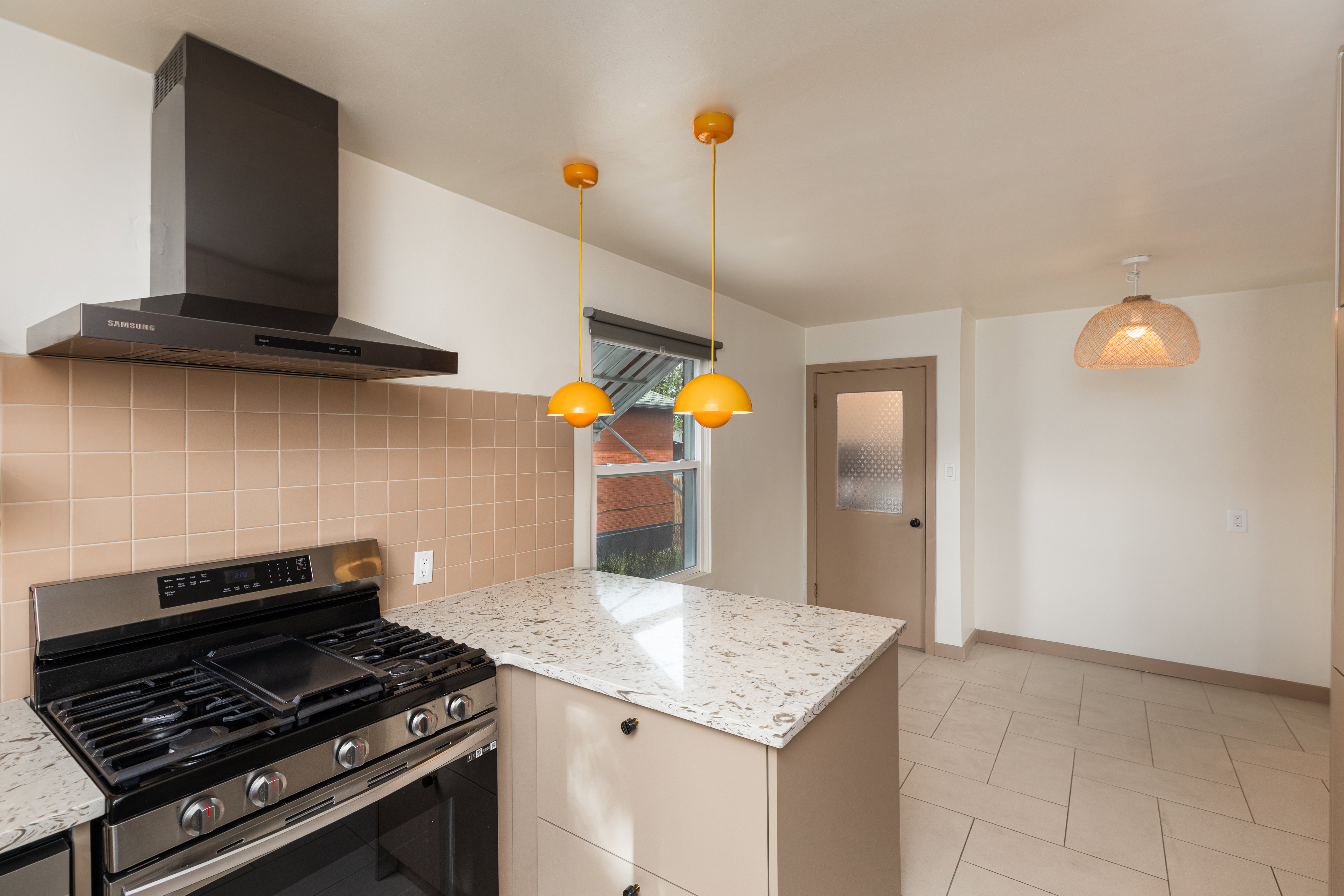 Kitchen featuring a stainless steel range with a mounted hood, light-toned tiled backsplash, and a countertop island