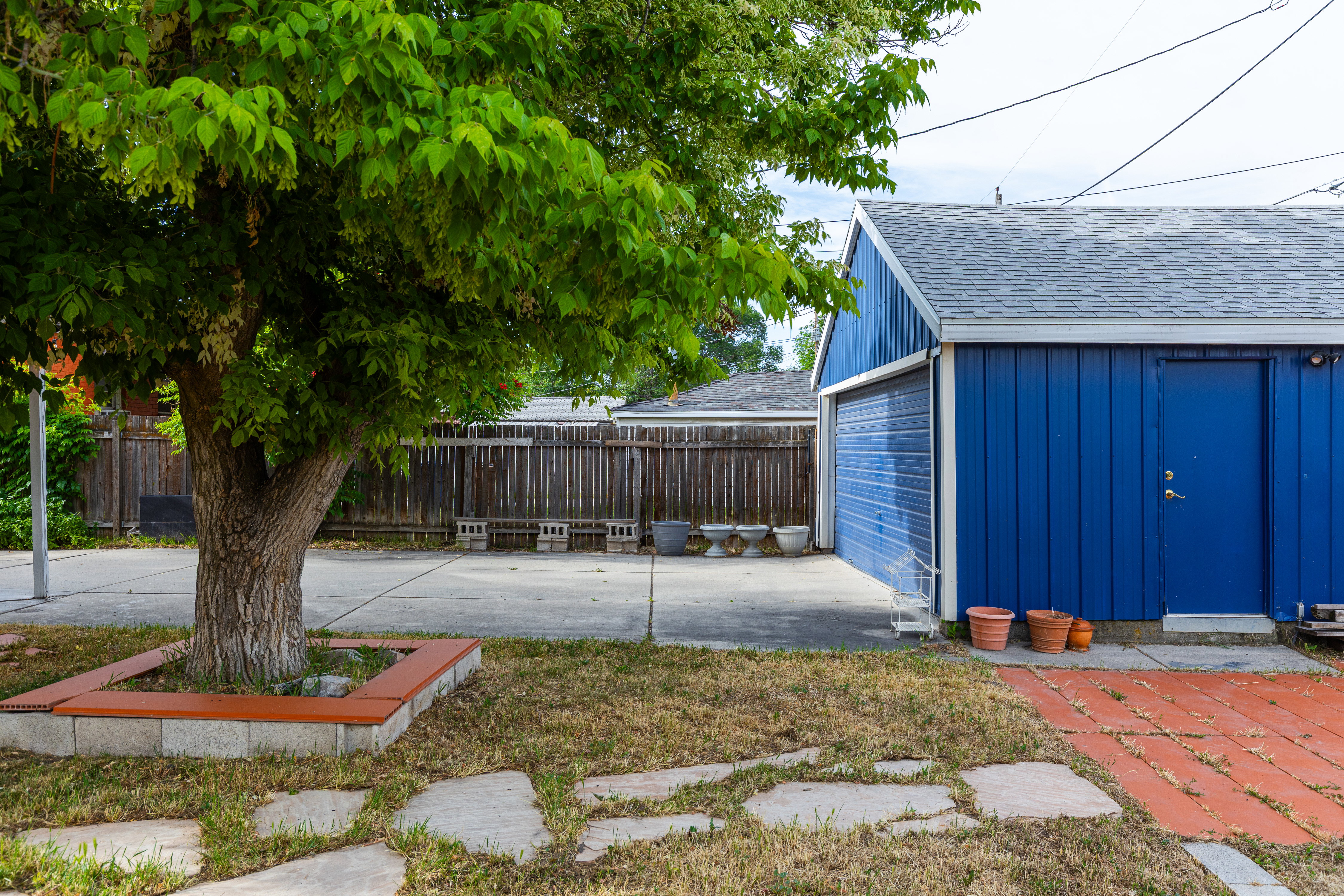 Detached blue garage structure with a rolling door and a pedestrian access door
