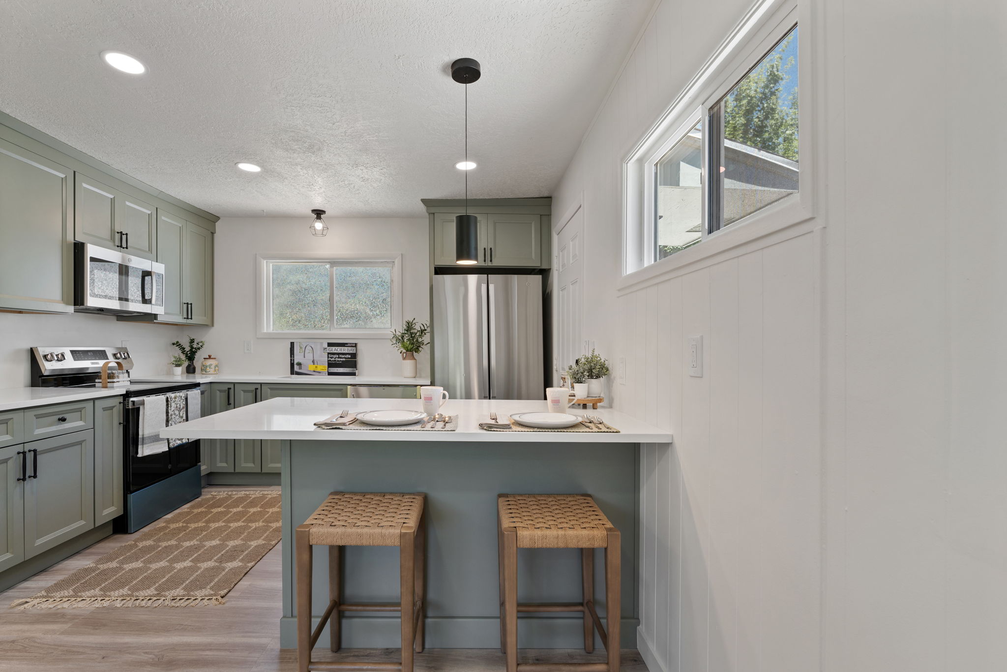 Modern kitchen featuring sage green cabinetry, stainless steel appliances, and white countertops