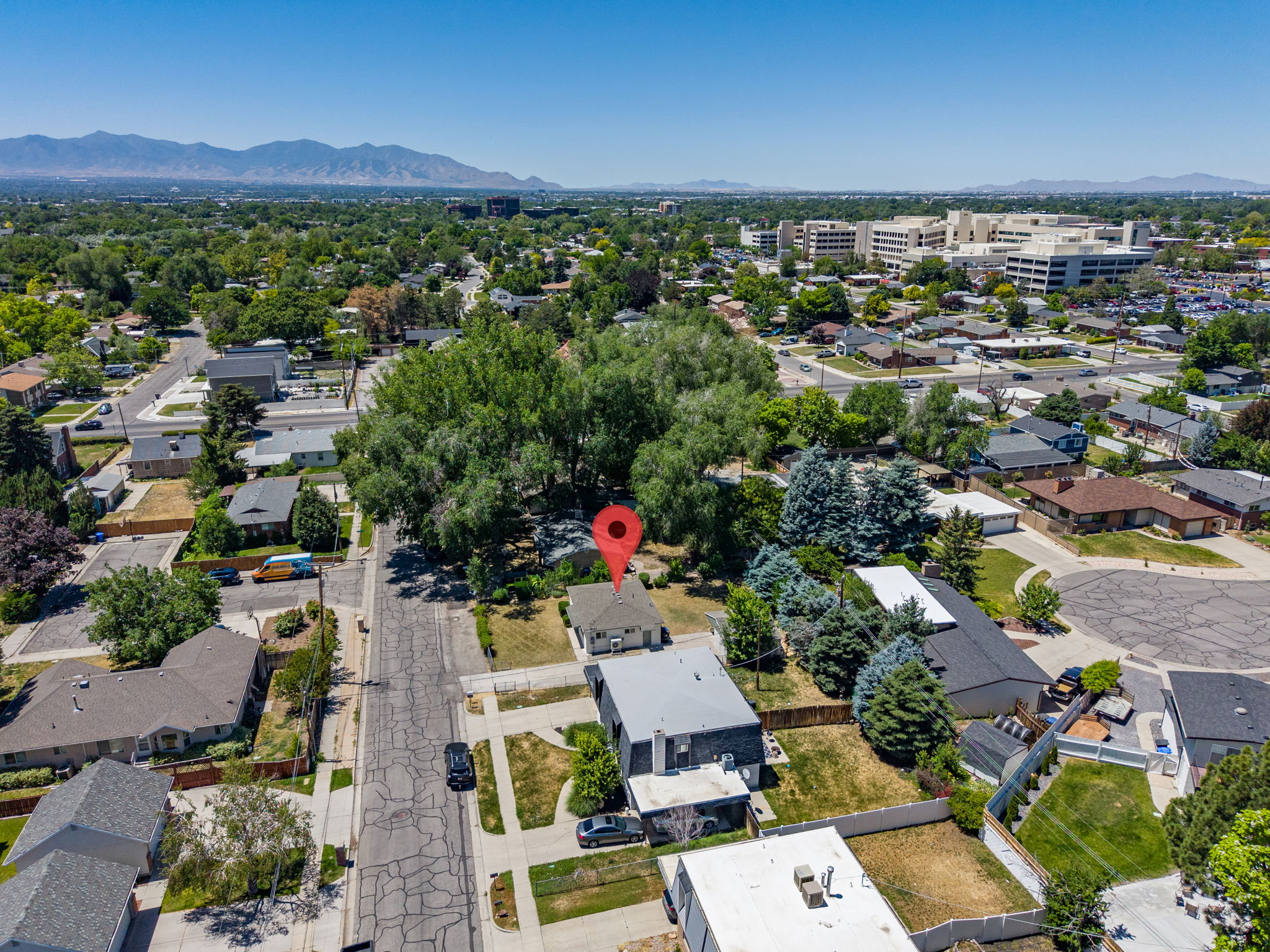 Aerial perspective showcasing a residential property with a detached garage, a fenced backyard, and mature landscaping