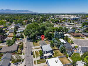 Aerial perspective showcasing a residential property with a detached garage, a fenced backyard, and mature landscaping