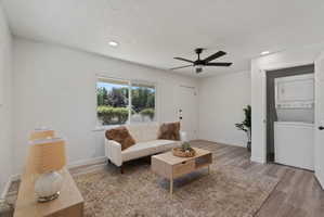 Living space featuring wood-finish flooring, a ceiling fan with integrated lighting, and recessed ceiling lights