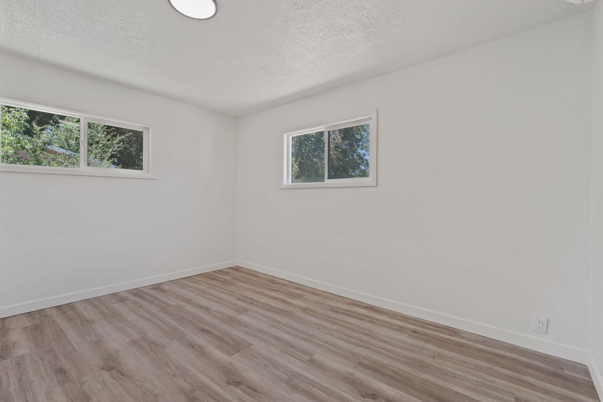 Room featuring wood-finish flooring, white baseboards, and neutral wall paint