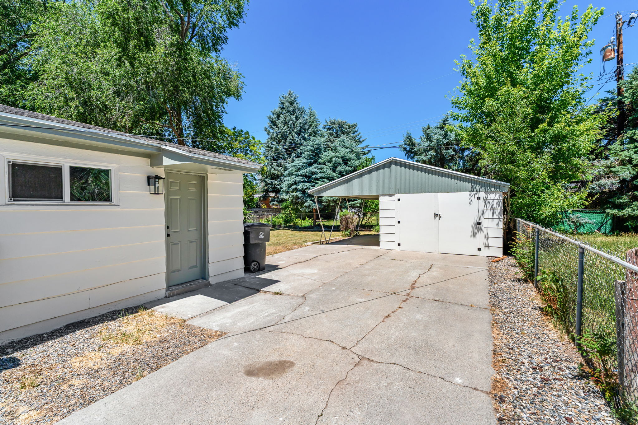 Detached garage structure with a carport and additional exterior storage building