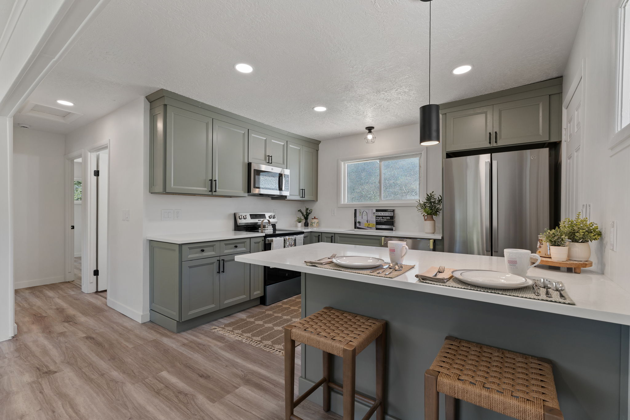 Kitchen featuring sage green cabinetry, stainless steel appliances, and white countertops