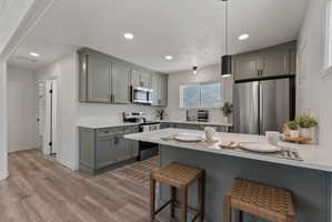 Kitchen featuring sage green cabinetry, stainless steel appliances, and white countertops