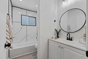 Contemporary bathroom featuring a white vanity with integrated sink, black-framed oval mirror, and matte black fixtures