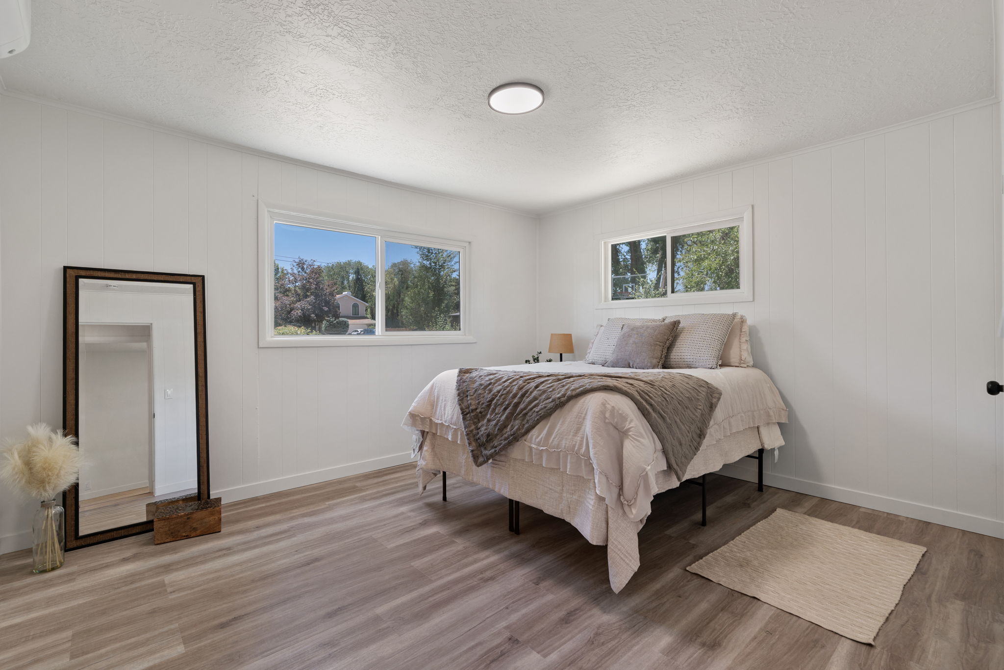 Light wood-finish flooring complements white walls with vertical paneling