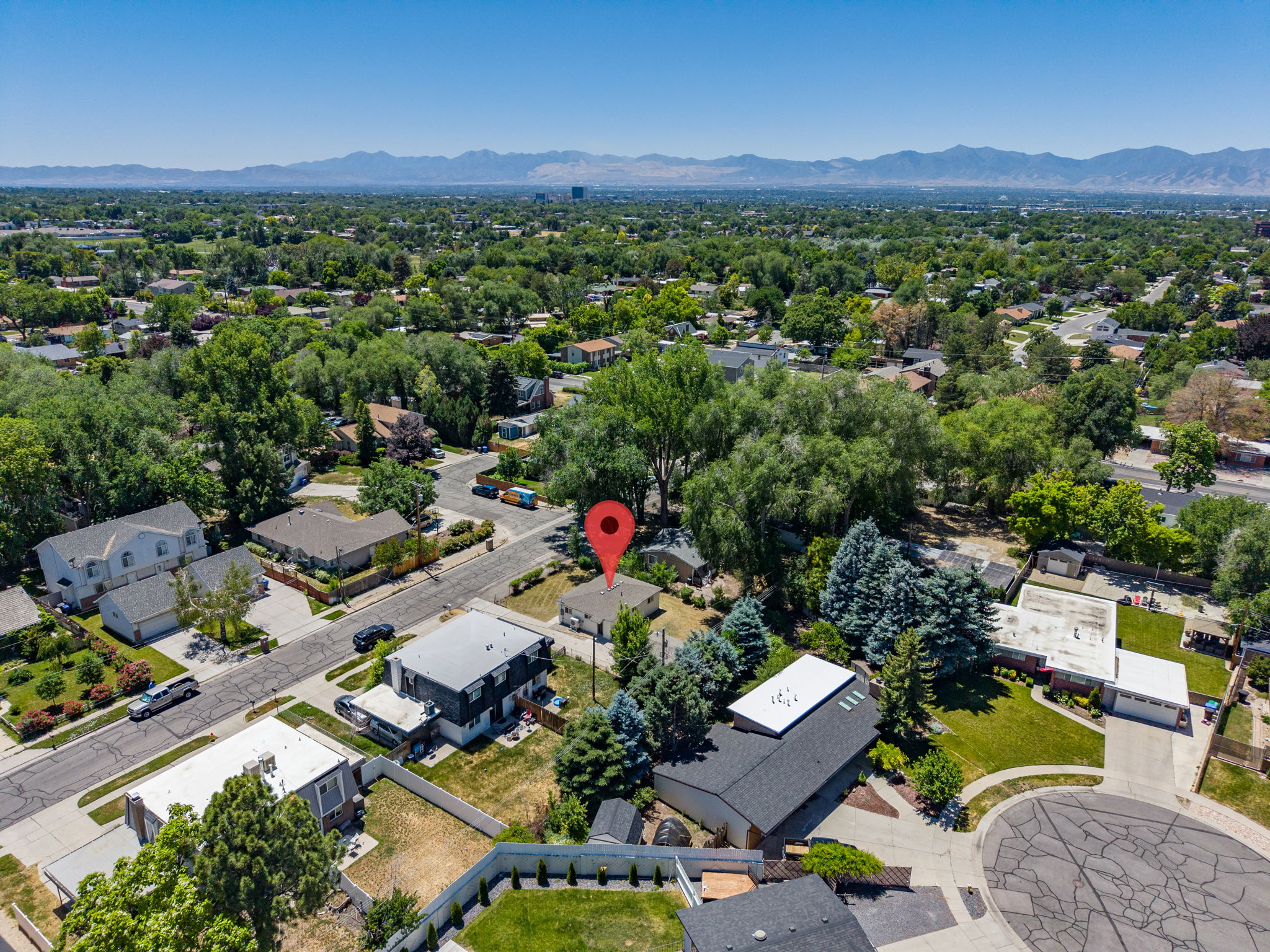 Aerial perspective showcasing the residential area with mature trees and a distant mountain range
