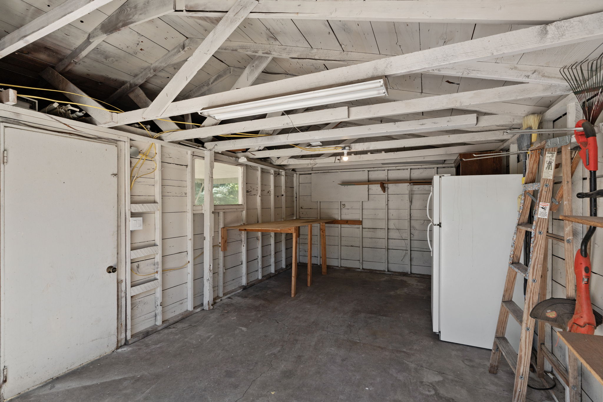 Utility space featuring exposed ceiling joists, a white painted door, and a built-in folding table