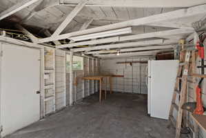 Utility space featuring exposed ceiling joists, a white painted door, and a built-in folding table