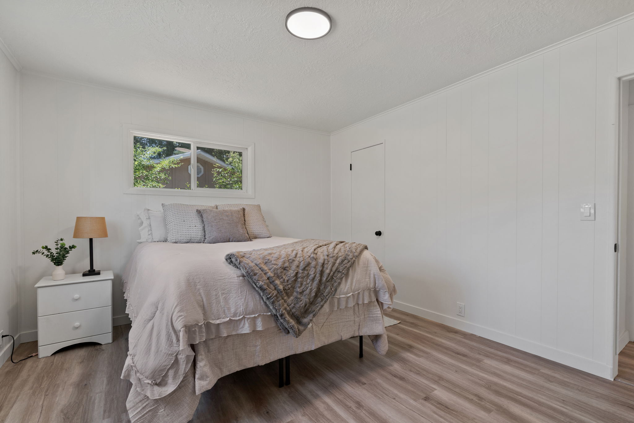 Bright interior space featuring wood-finish flooring, white paneled walls, and a recessed ceiling light fixture