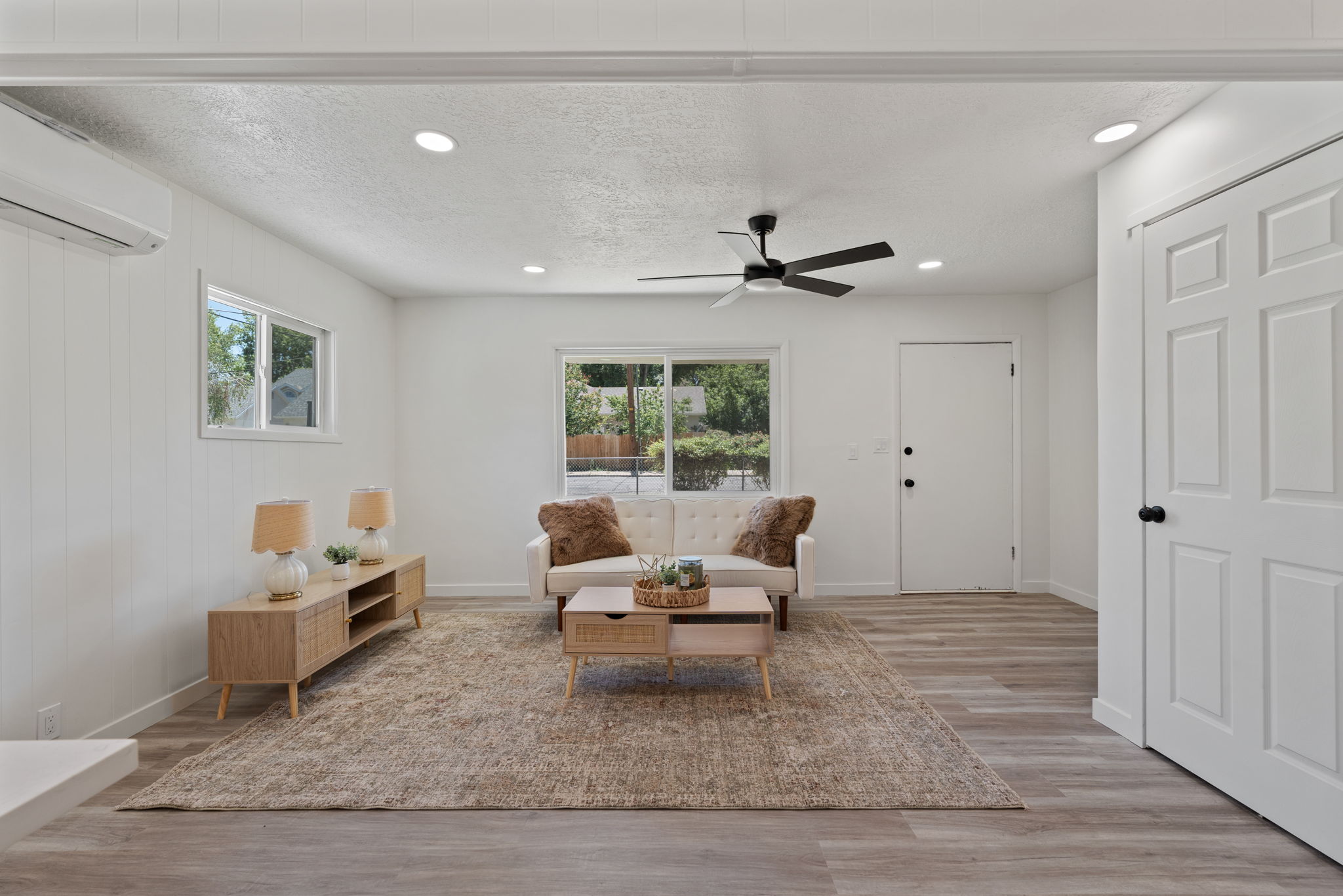 Spacious living area featuring light wood-finish flooring, recessed lighting, and a modern ceiling fan
