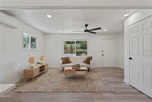 Spacious living area featuring light wood-finish flooring, recessed lighting, and a modern ceiling fan