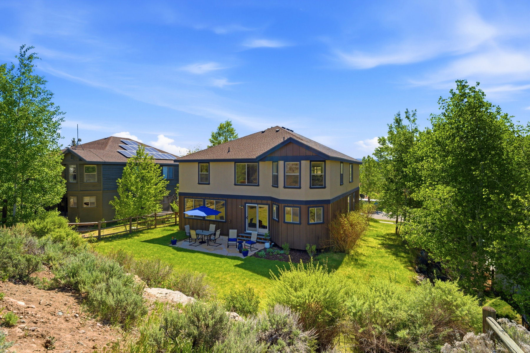Rear exterior featuring a patio, manicured lawn, and mature landscaping
