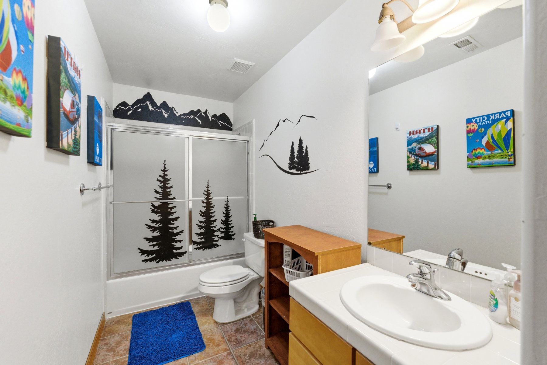Bathroom featuring a built-in tub with sliding glass shower doors, white toilet, and a vanity with an integrated sink