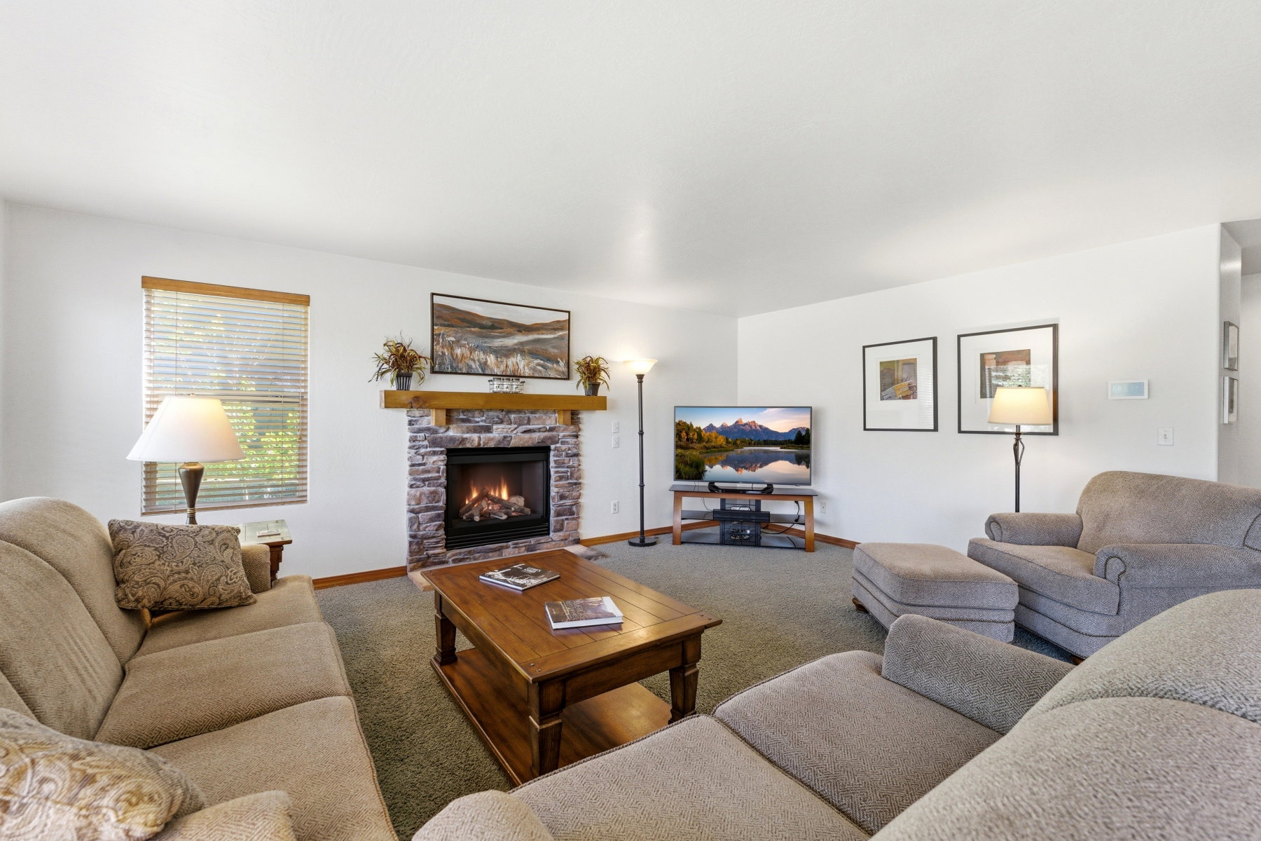 Living area featuring a stone-faced fireplace with wood mantel, carpet flooring, a window with horizontal blinds, and recessed lighting
