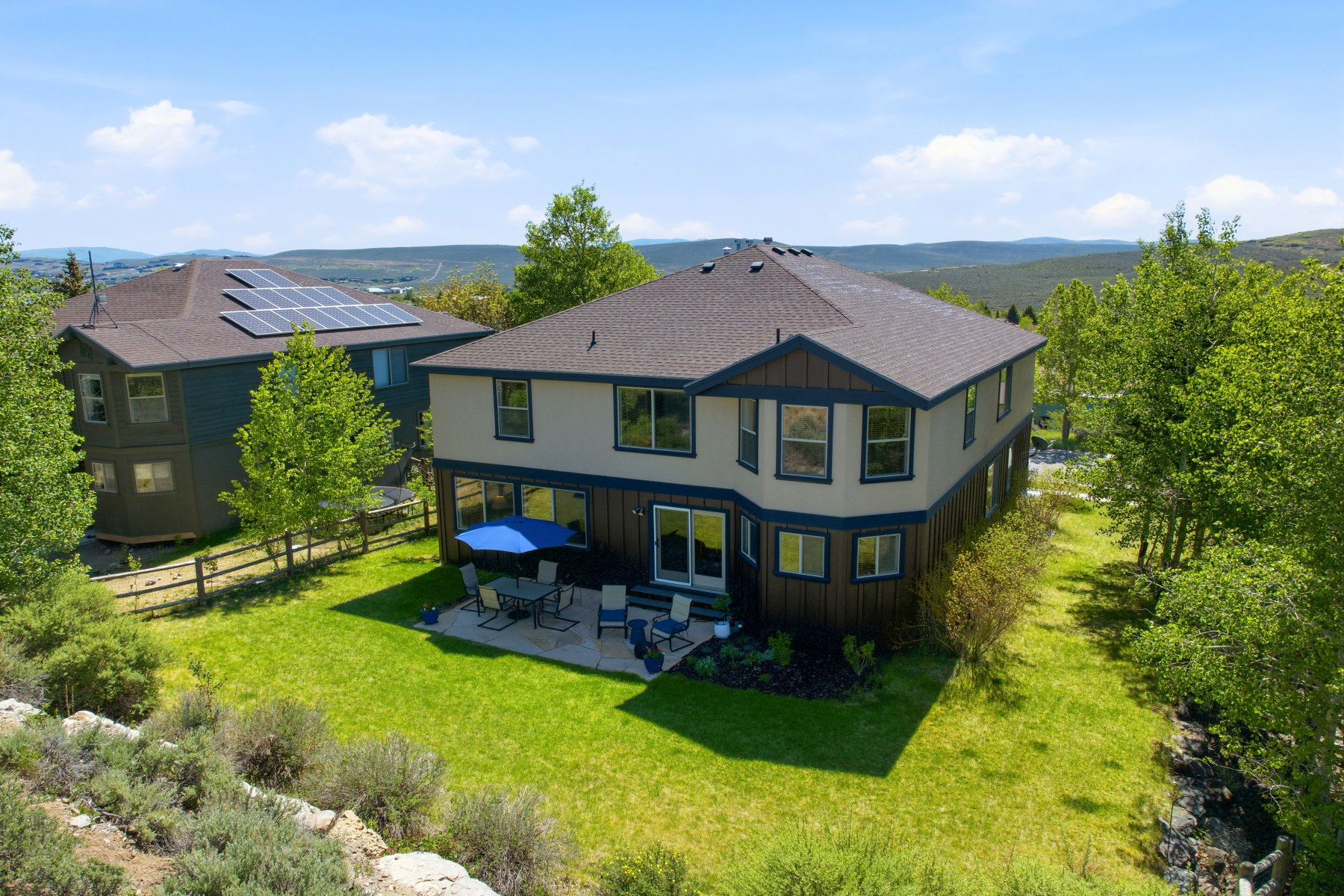 Rear exterior featuring a patio, sliding glass doors, and a manicured lawn