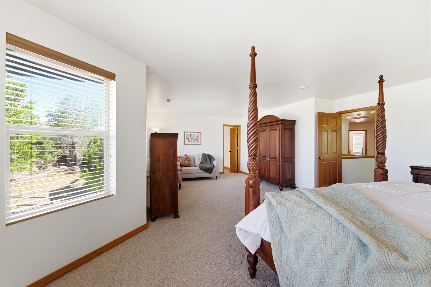 Carpeted interior with white walls, wood-finish trim, and a window featuring white blinds