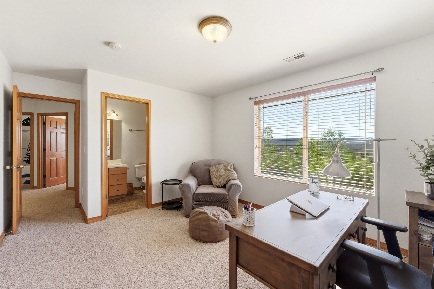 Carpeted room featuring a large window with horizontal blinds, offering expansive outdoor scenery