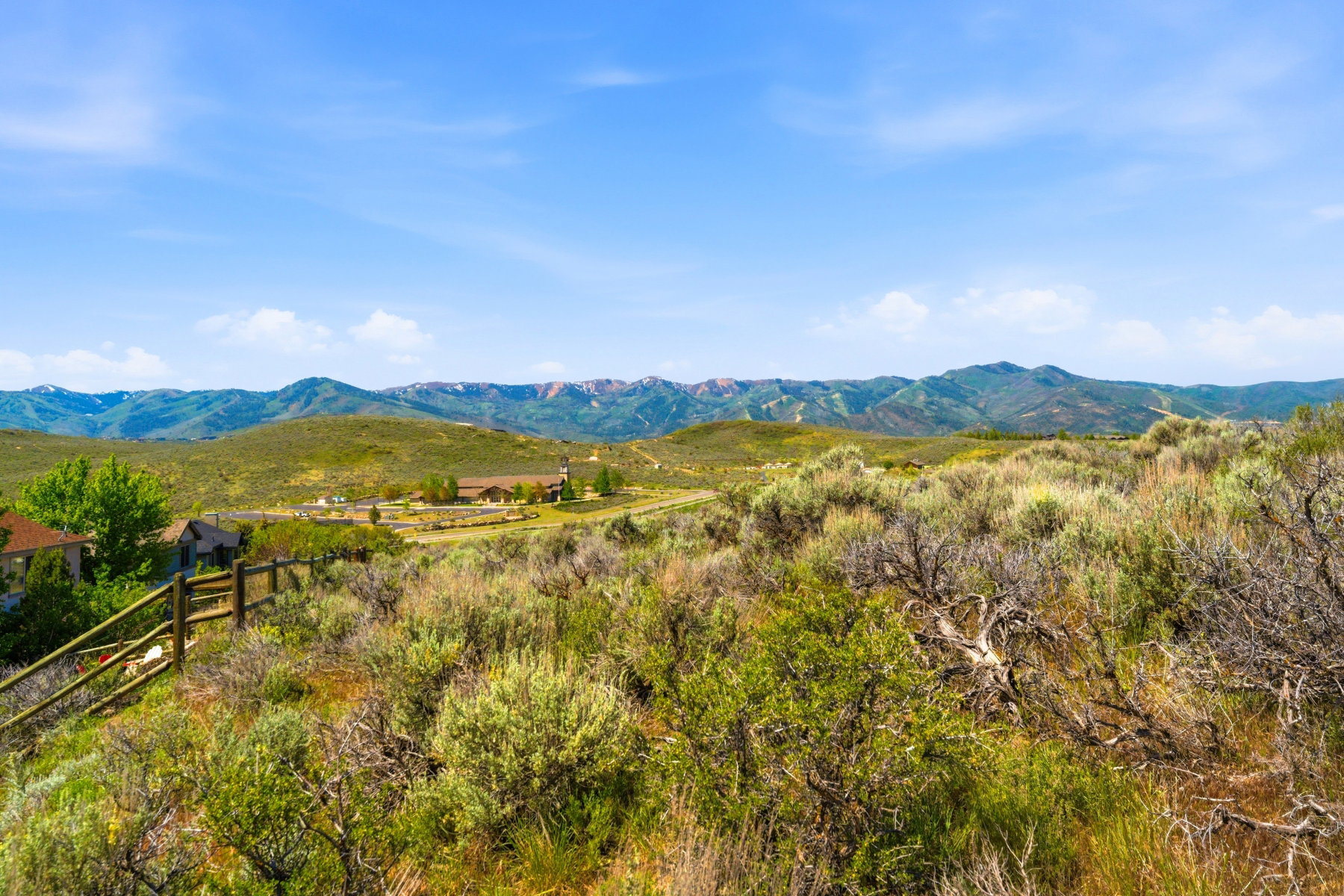 Expansive natural landscape featuring rolling hills, distant mountains, and a clear blue sky