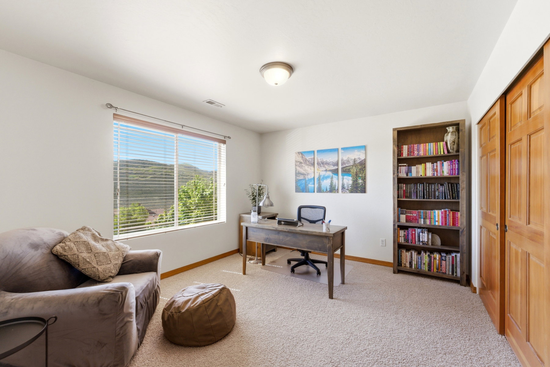 Bright room with neutral carpeting and a large window featuring horizontal blinds