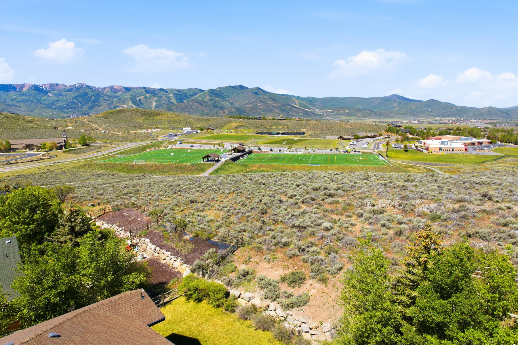 Expansive mountain landscape with a visible sports field complex and a distant school building