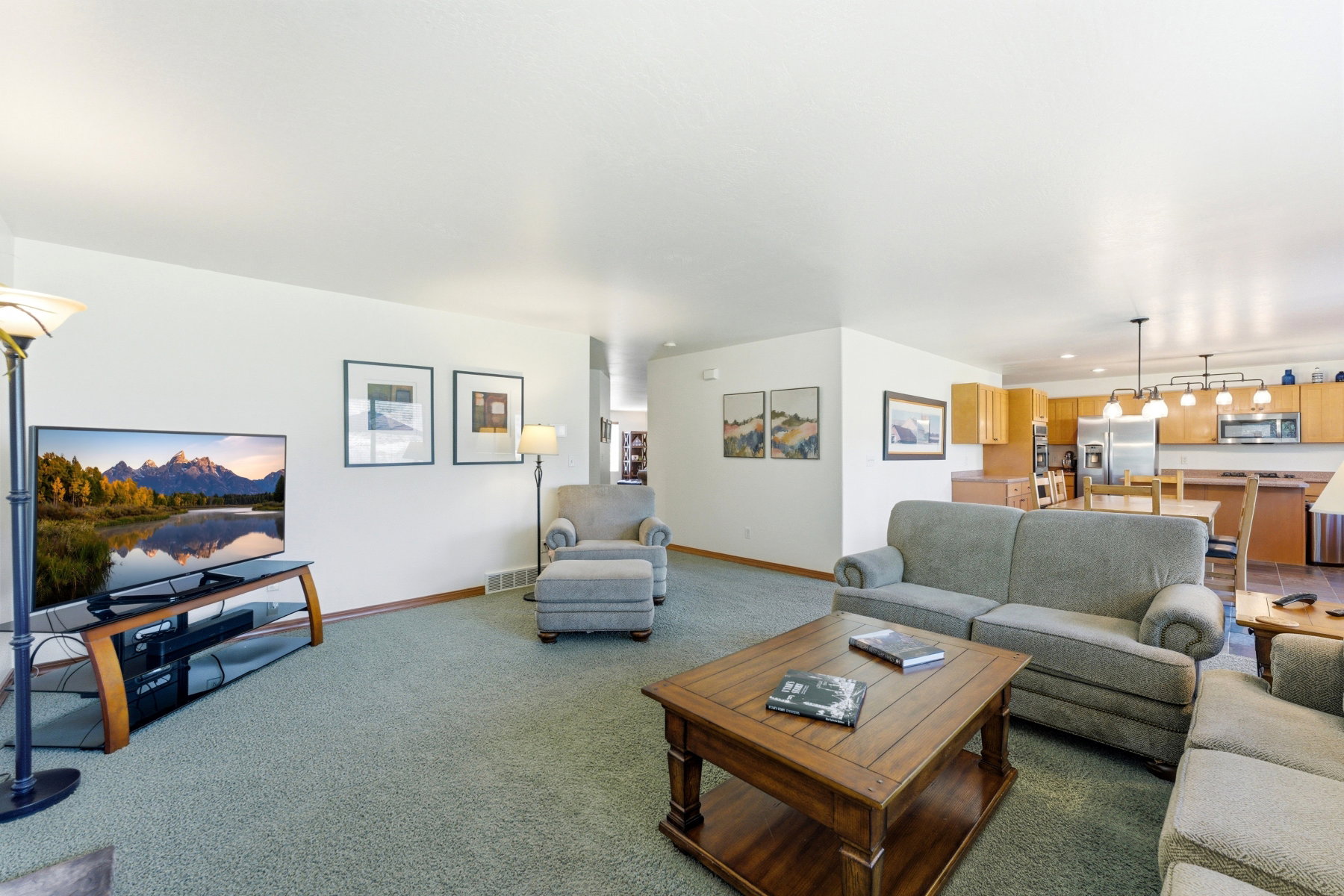 Open-concept living space featuring light green carpet flooring and white painted walls