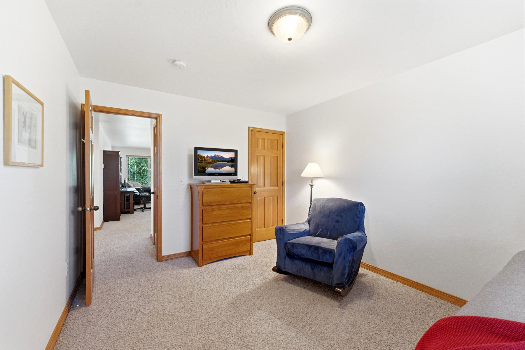 Carpeted room featuring light-toned walls, wood-finish trim, and a flush-mount ceiling light fixture