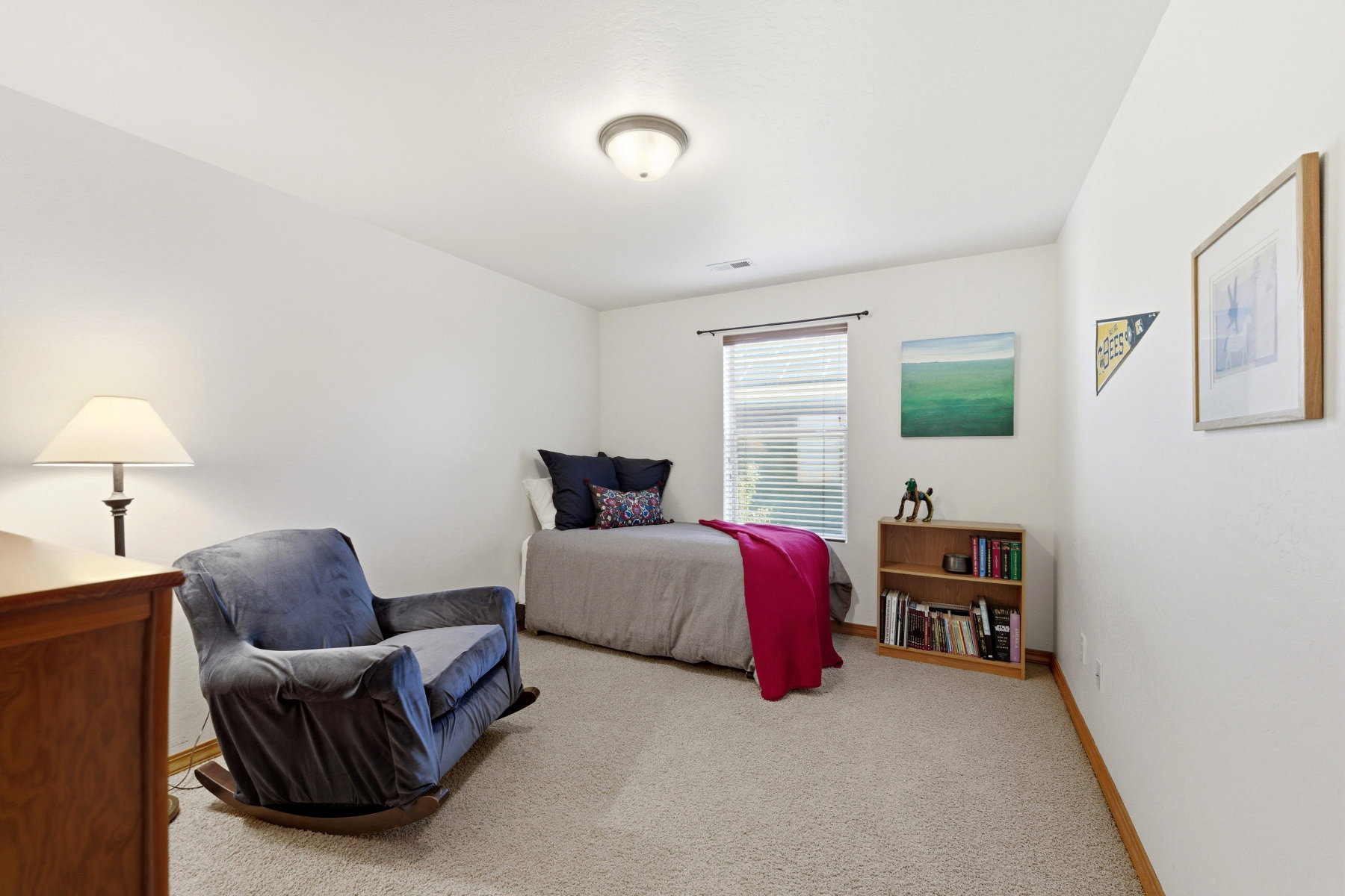 Bedroom featuring light neutral carpeting, white walls, a ceiling-mounted light fixture, and a window with blinds