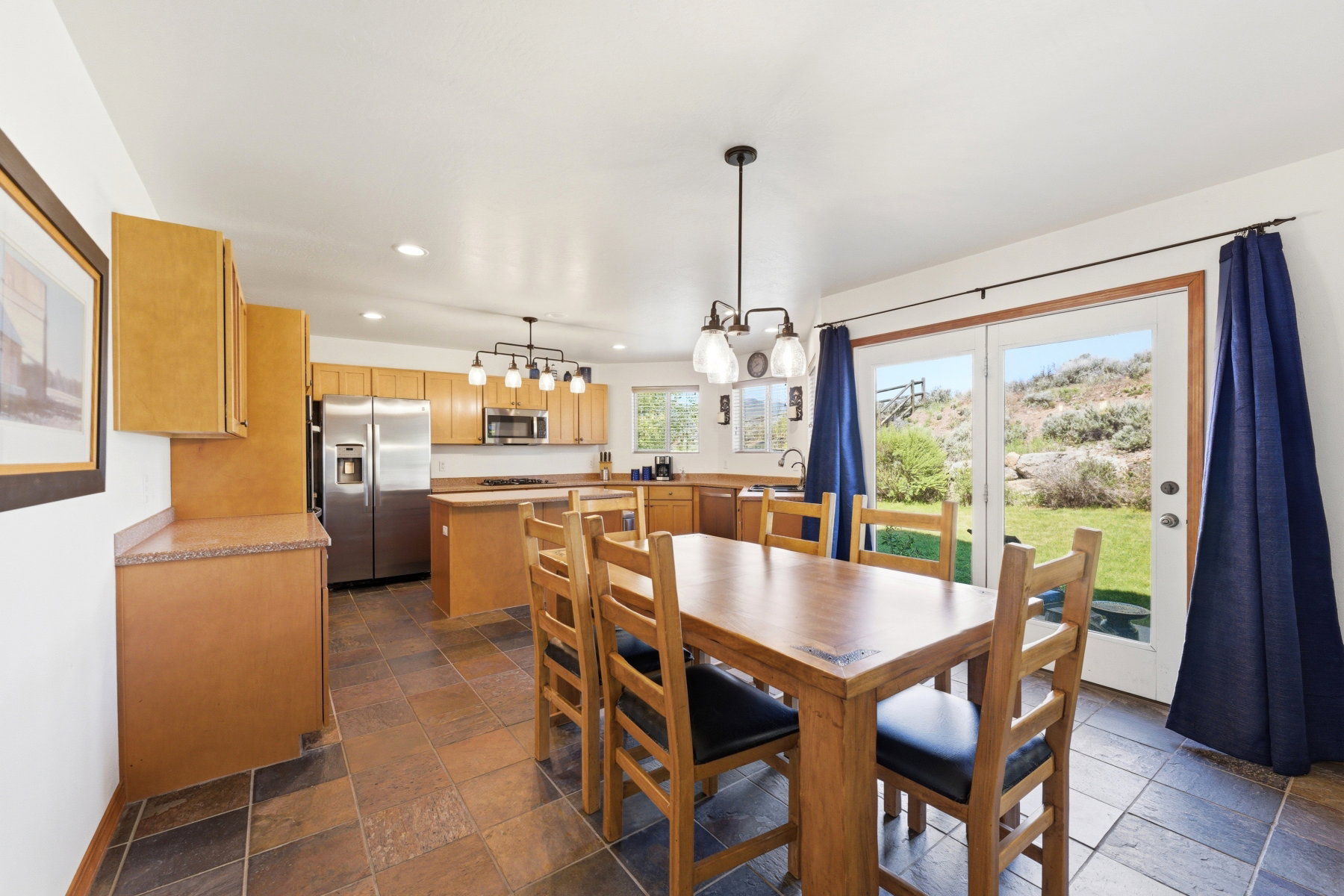 Kitchen and dining area featuring wood cabinetry, stainless steel appliances, and tiled flooring