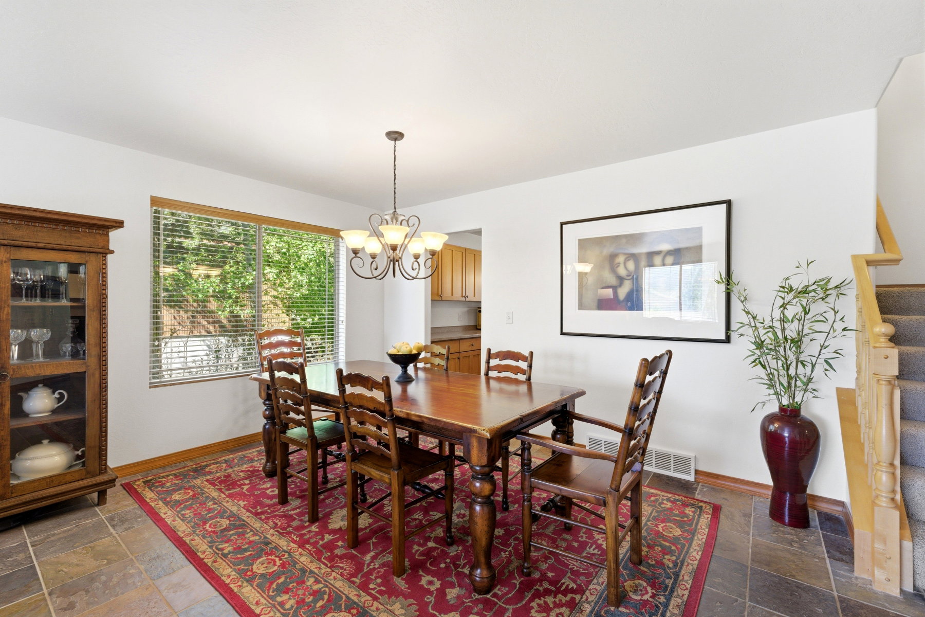 Dining space featuring large window with blinds, overhead chandelier, and tile flooring