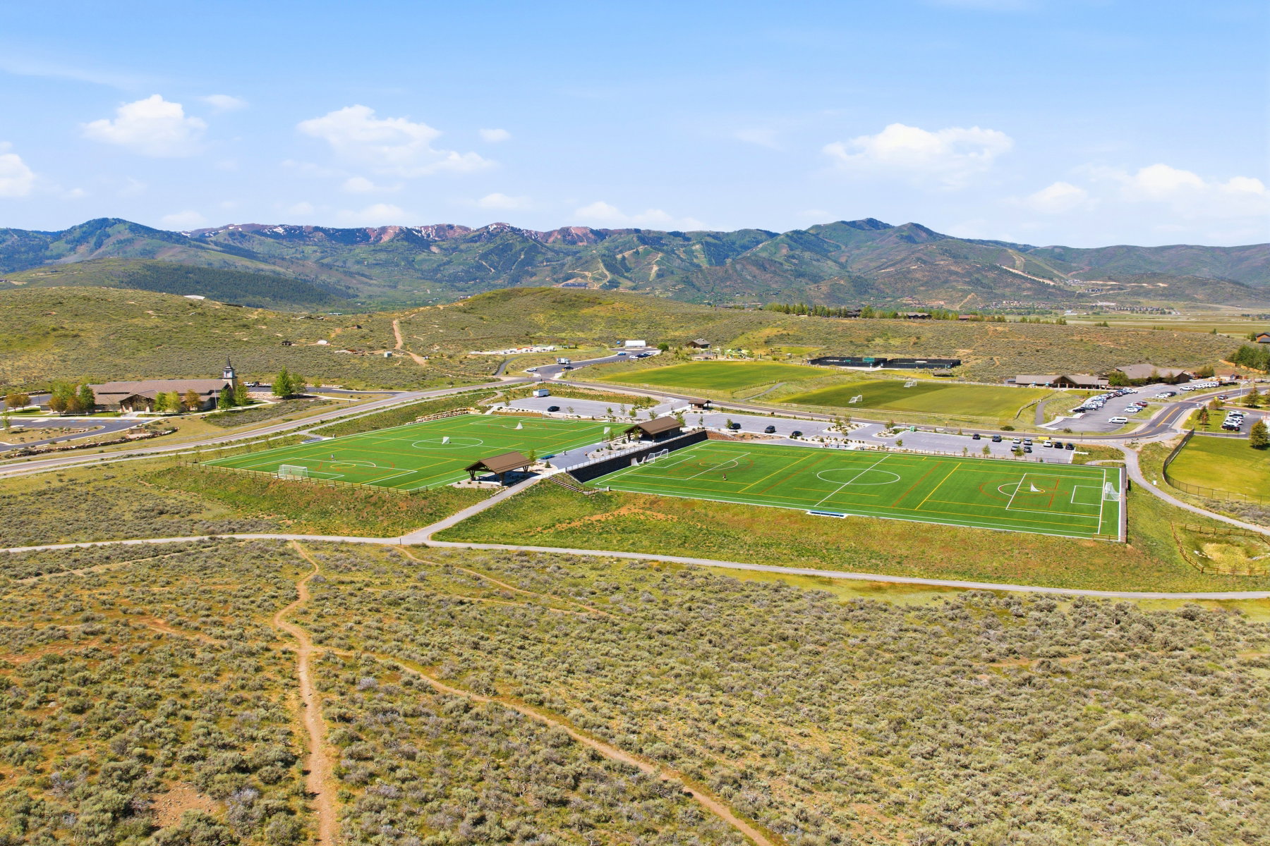 Expansive athletic complex featuring multiple turf fields, spectator seating, and mountain backdrops