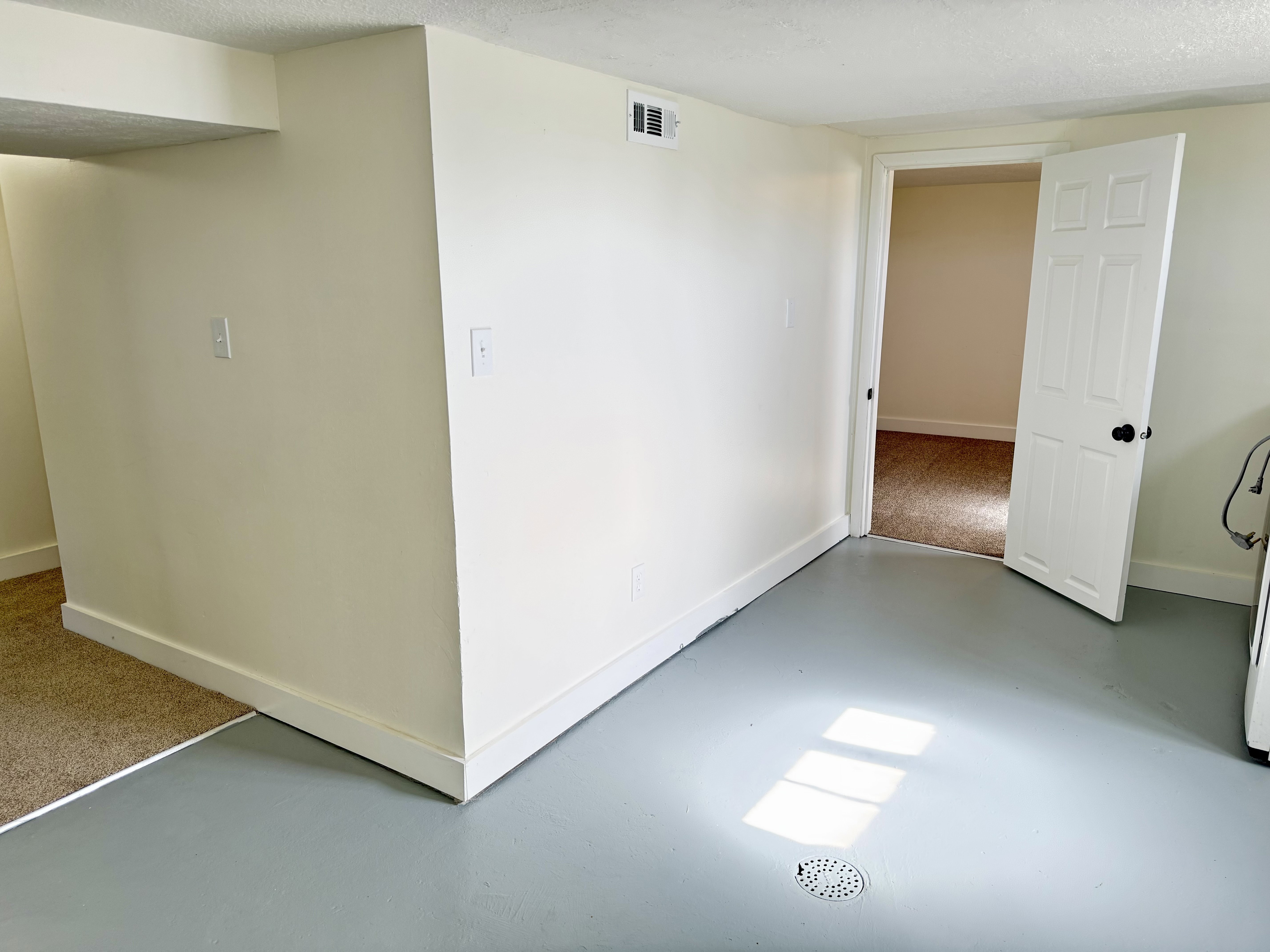 Expansive room featuring light gray finished concrete flooring and a floor drain