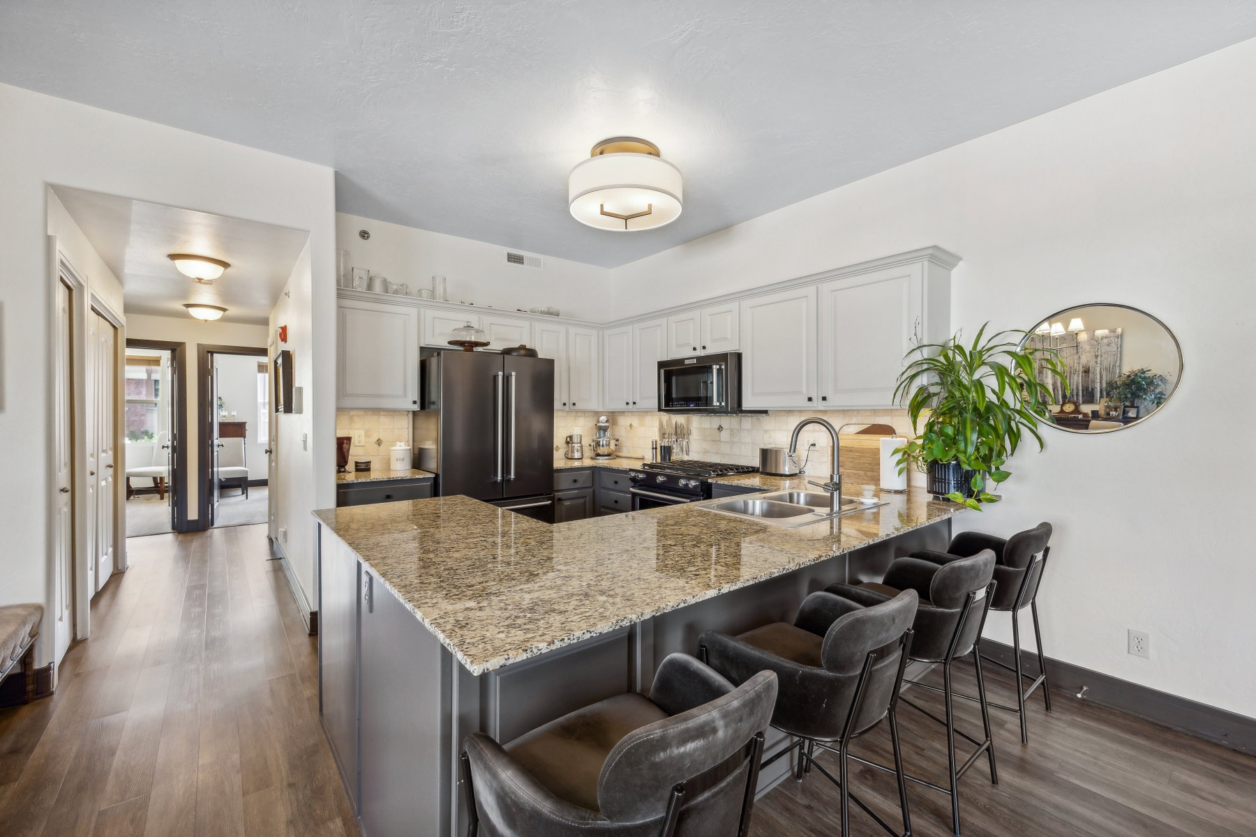 Kitchen featuring an expansive island with a granite countertop, undermount sink, and seating for multiple individuals