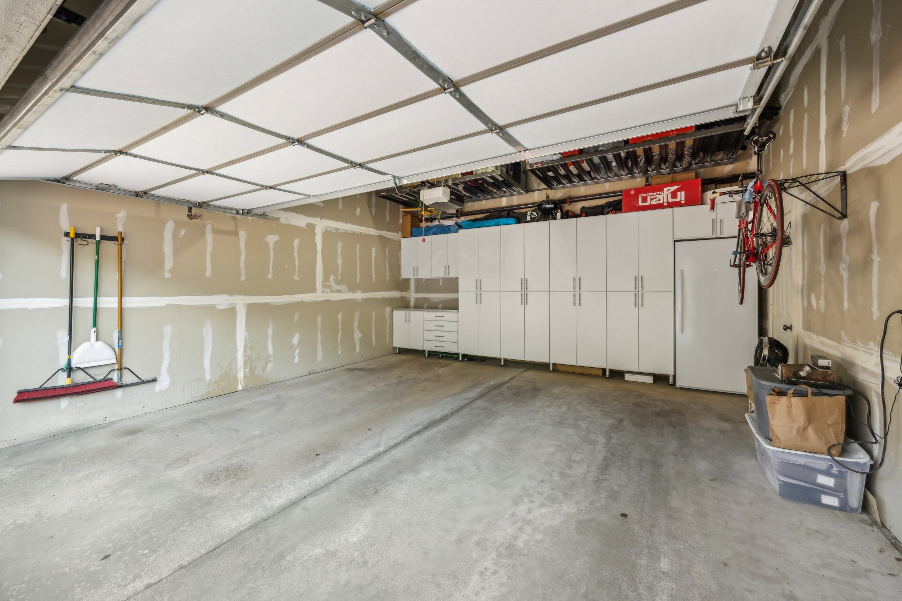 Attached garage featuring an overhead garage door, built-in white cabinetry, a built-in refrigerator, and concrete flooring