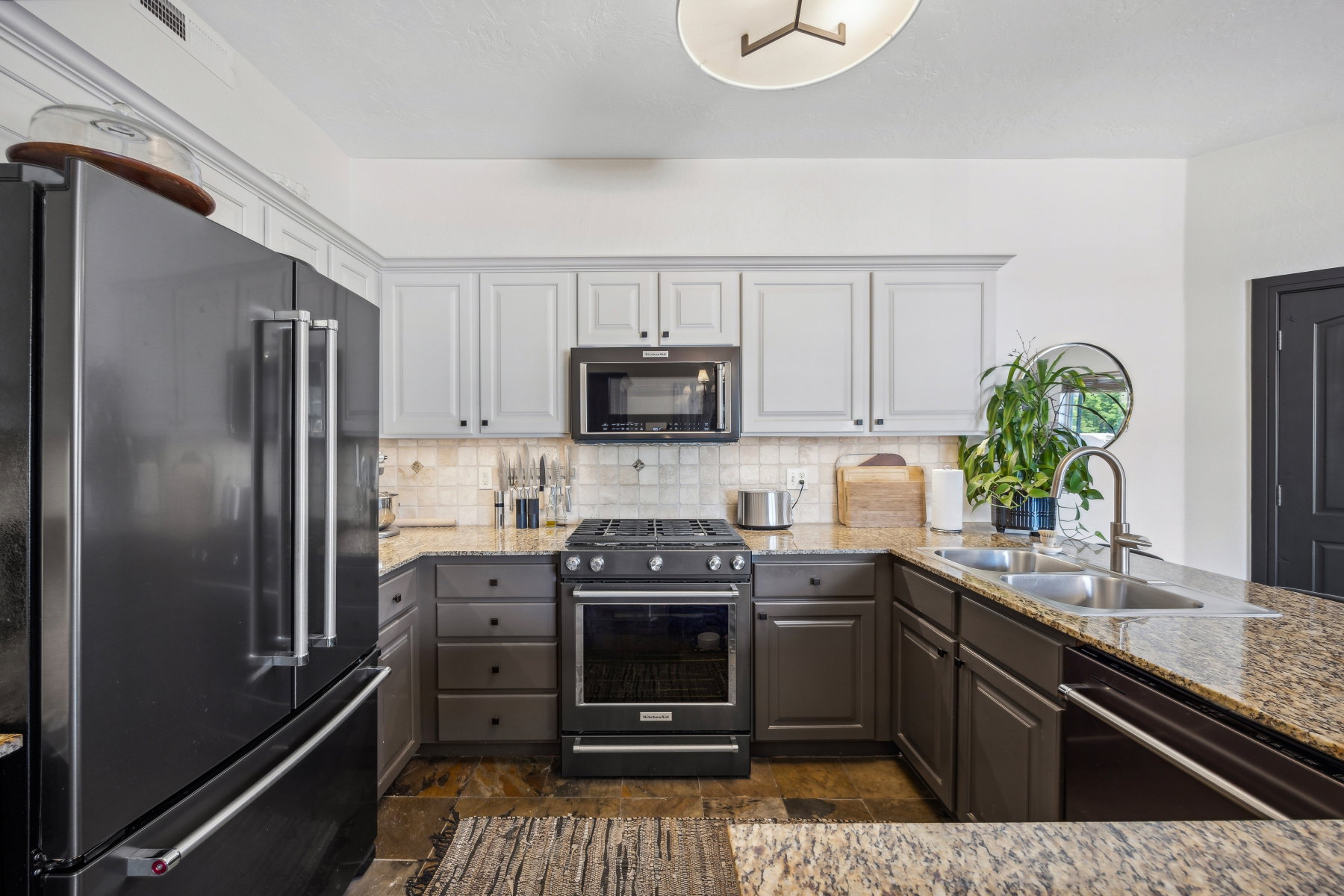 Kitchen featuring a black stainless steel refrigerator, granite countertops, and a dual-basin stainless steel sink with a gooseneck faucet