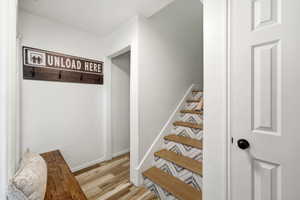 Entryway featuring wood-finish flooring, a white paneled door with a black knob, and a staircase with wood treads and patterned risers