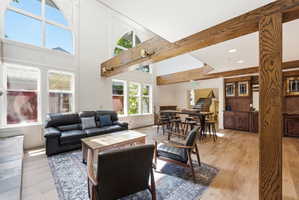 Spacious common area featuring a high vaulted ceiling, exposed wood beams, and extensive natural light through large windows